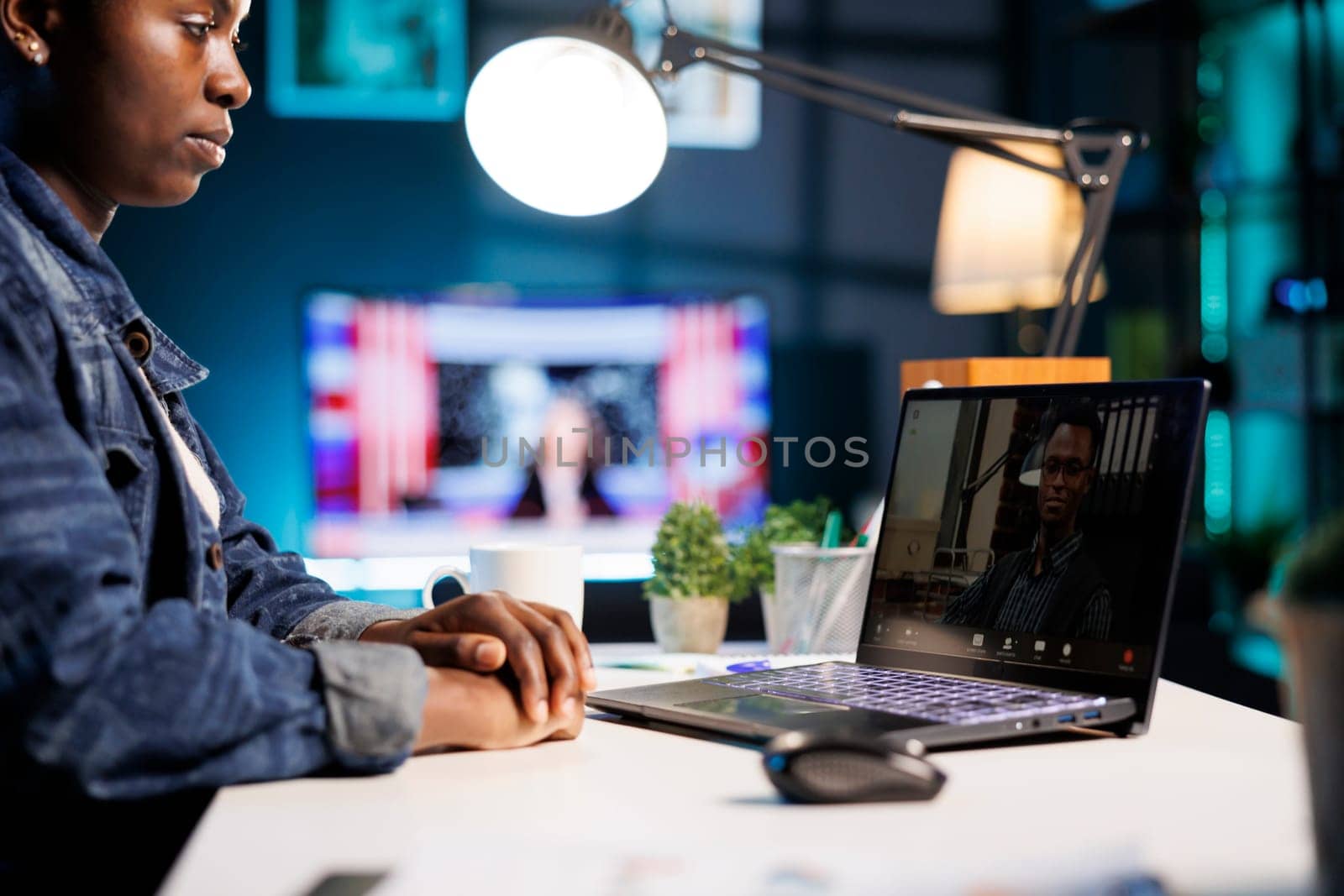 Close-up of african american freelancer sitting at table at home having video conference with male colleague. Female college student studying online with laptop, virtual communication with professor.