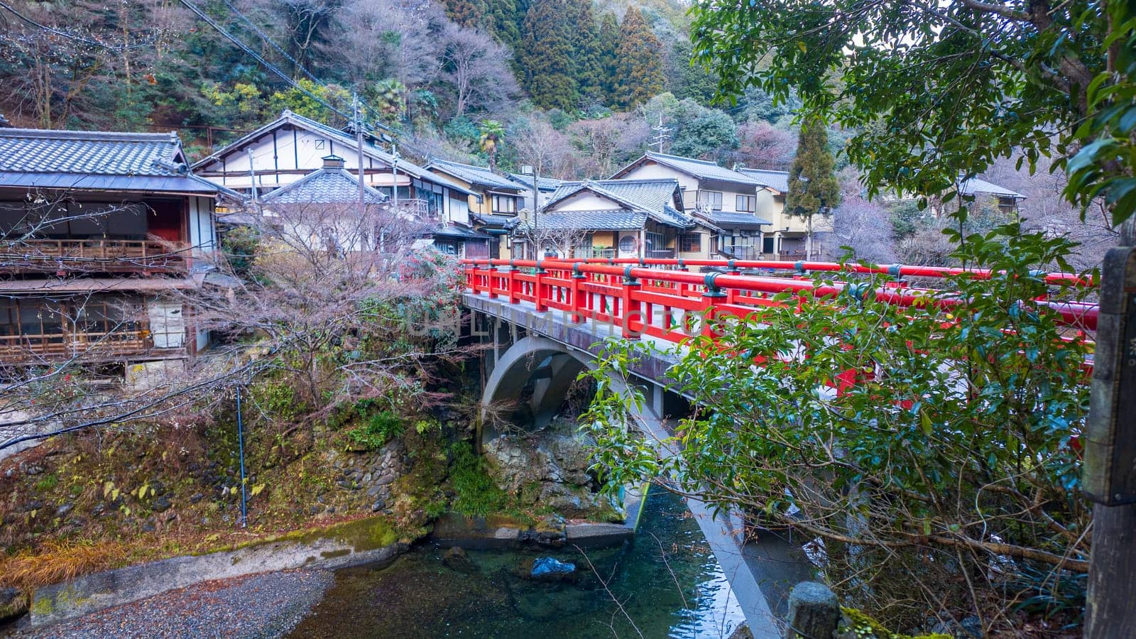 Red bridge over small river by traditional Japanese village. High quality photo