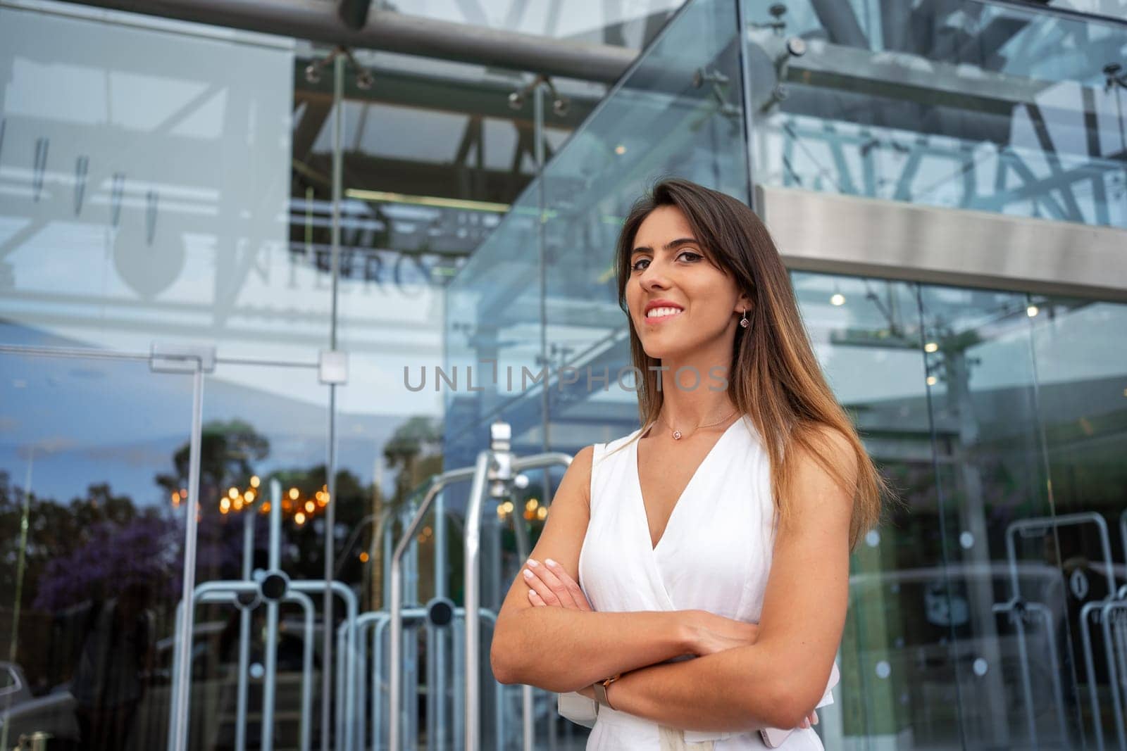 Portrait of smiling successful businesswoman standing arms crossed looking at camera. Confident female entrepreneur outside corporate building.