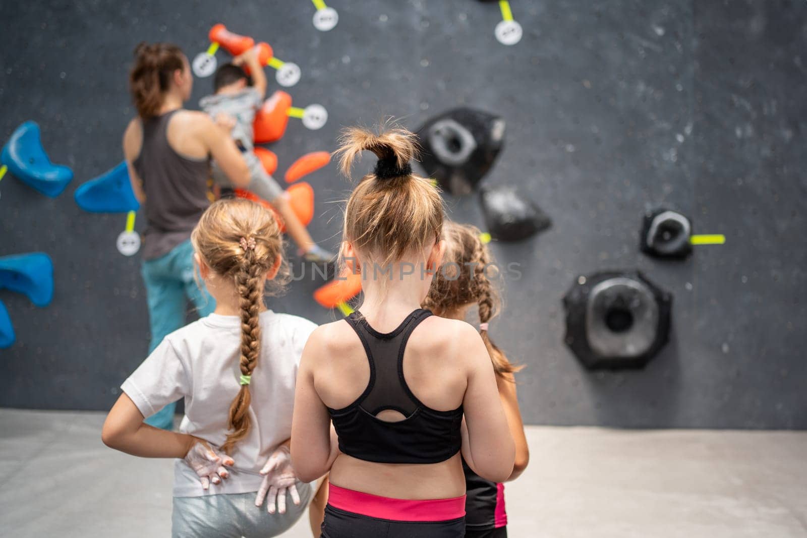 Young girls training in wall climbing class at gym by andreonegin