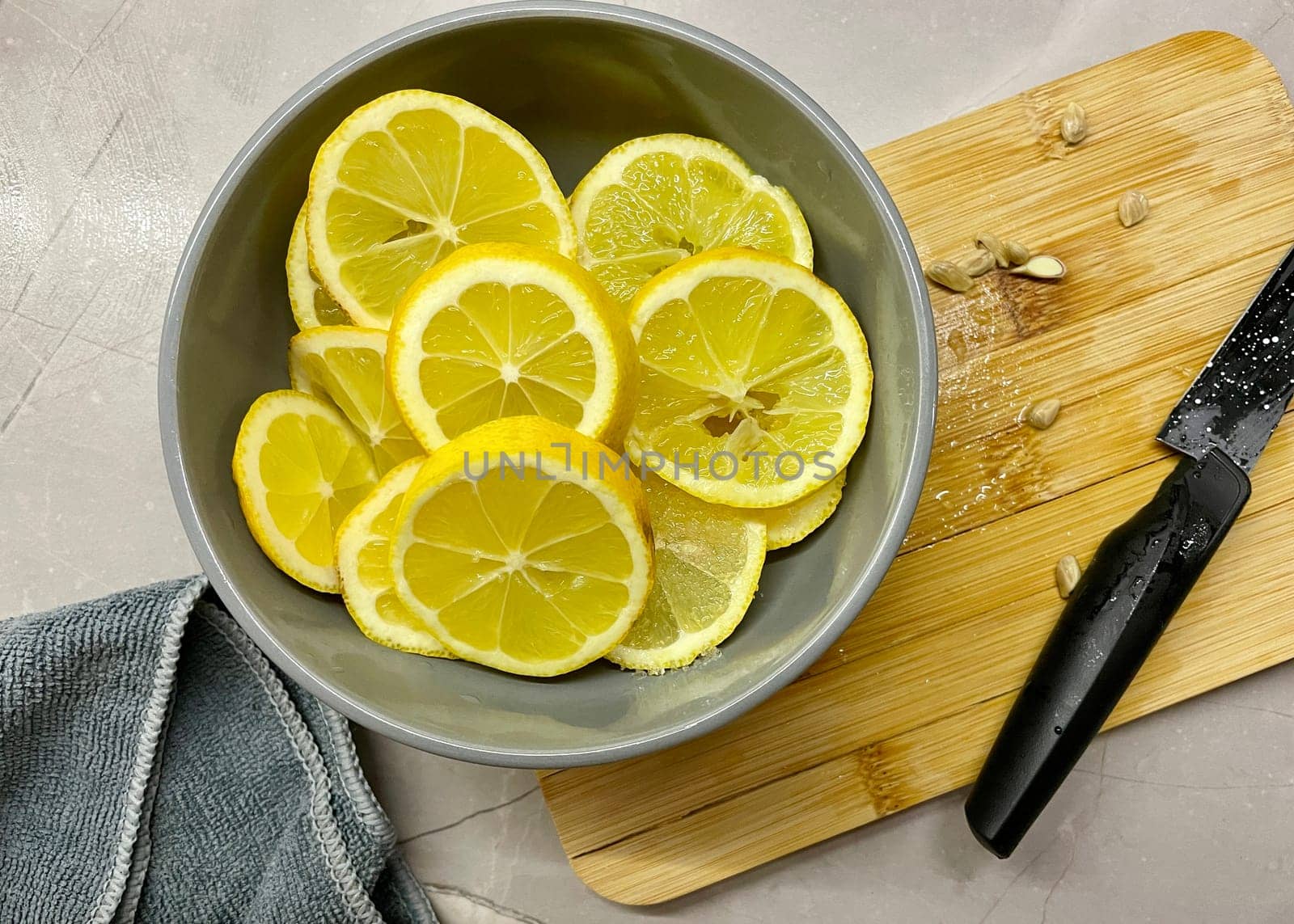 Pieces of lemon lie on a gray round plate standing on a wooden board. High quality photo