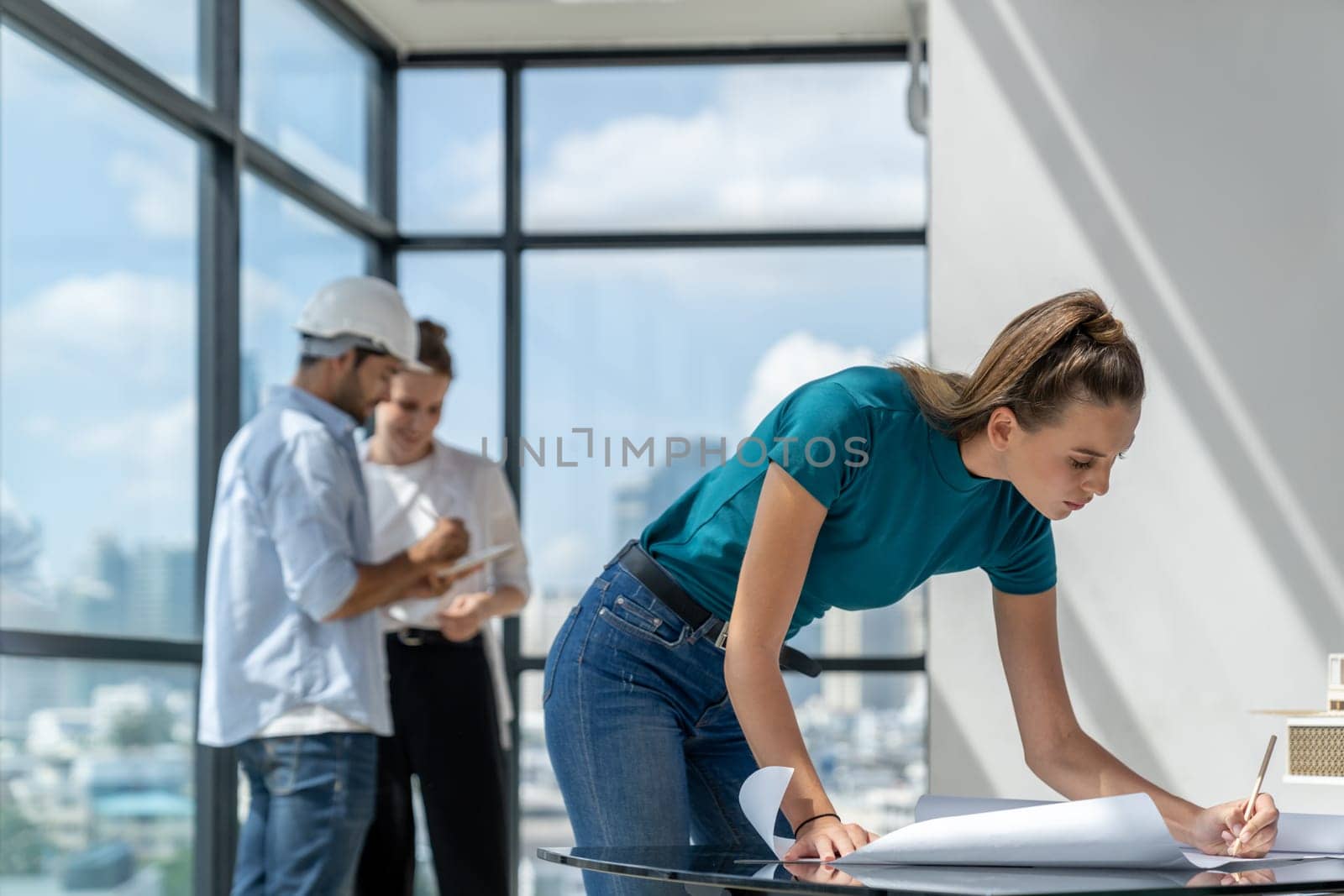 Young beautiful architect drawing blueprint while professional engineer discussing about house design. Skilled engineer team sharing idea. Civil engineering, working together, brainstorming. Tracery.