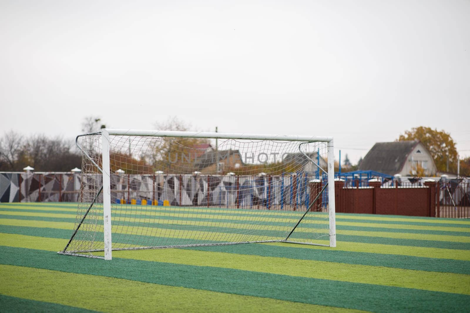 a small green soccer field and a white gate. High quality photo