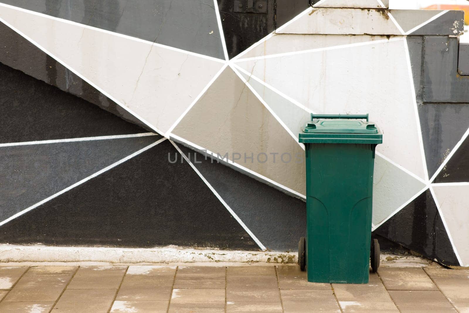 green garbage can near the wall. High quality photo