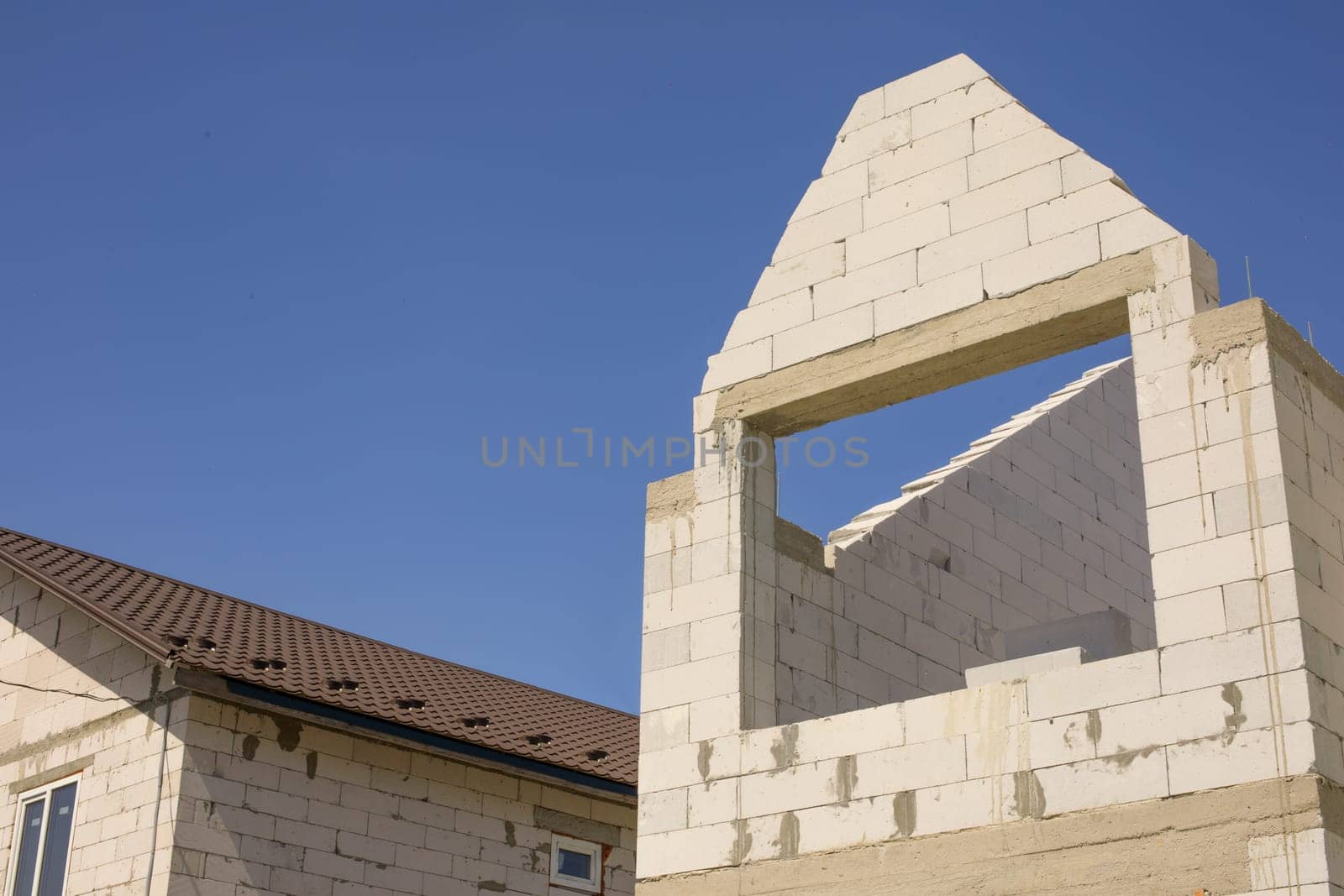 small construction of a house, with white bricks or foam block, against the background of the sky. High quality photo