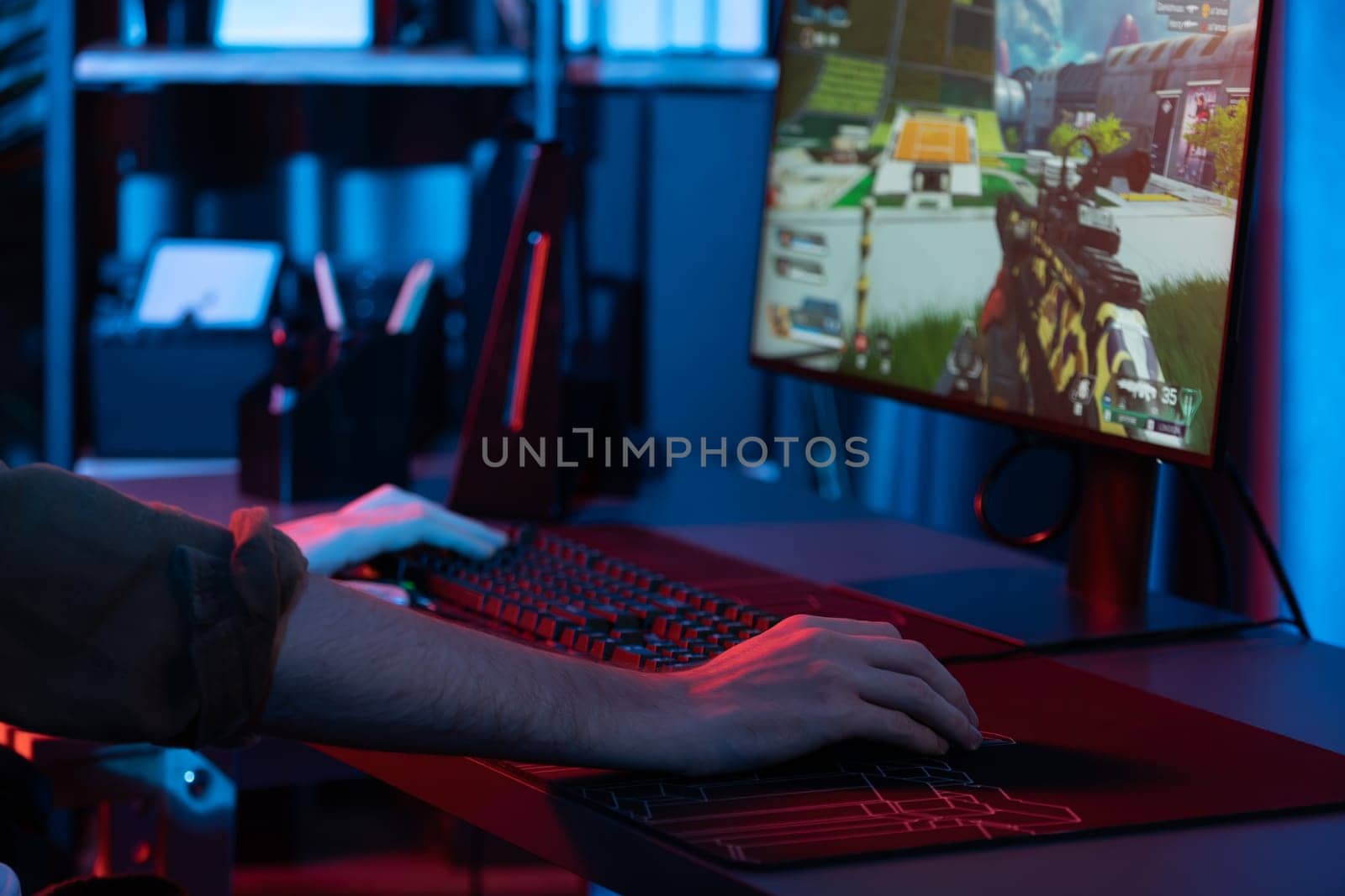 Host channel of young gaming streamer, team gamer playing battle game with multiplayer at warship on pc screen with cropped back side image, wearing headset with mic at digital neon room. Gusher.