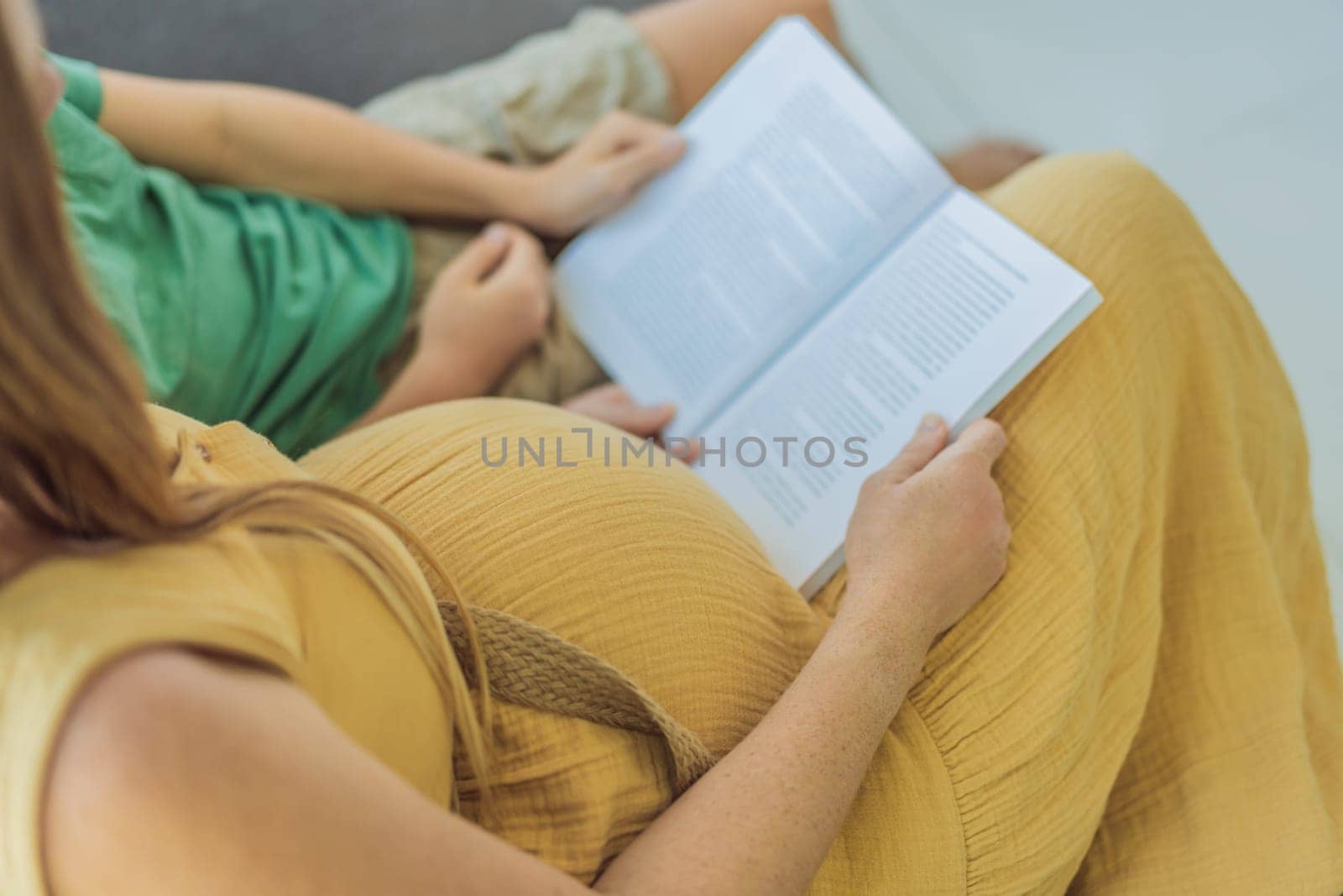 Sweet and bonding moment as a pregnant mother and her son share quality time, immersed in a book, creating cherished memories through the joy of reading together.