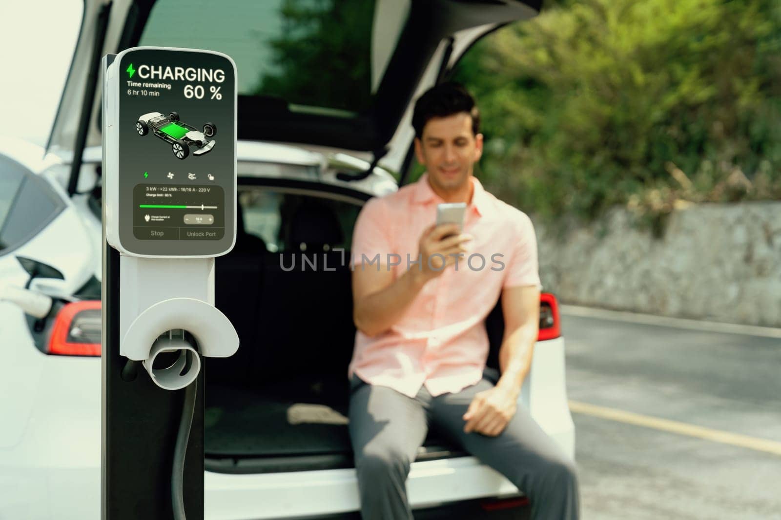 Electric car recharging battery from EV charger with blur background. Perpetual by biancoblue