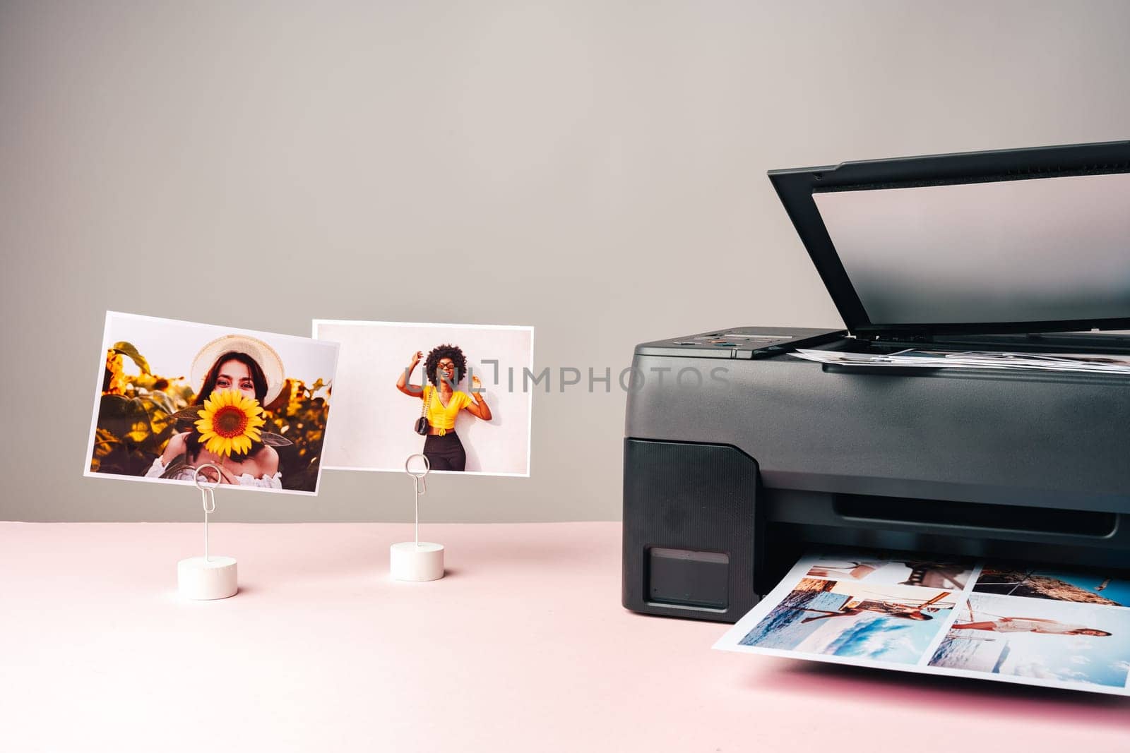 Modern laser printer printing color photos of women close up on desk