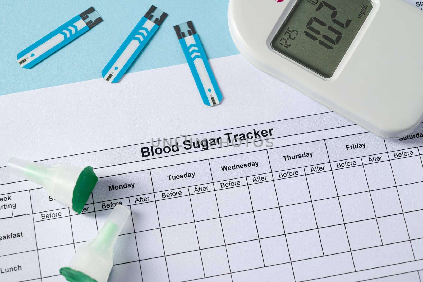 Top view of glucometer, lancet pen, strips and blood sugar tracker on blue background. diabetes test kit