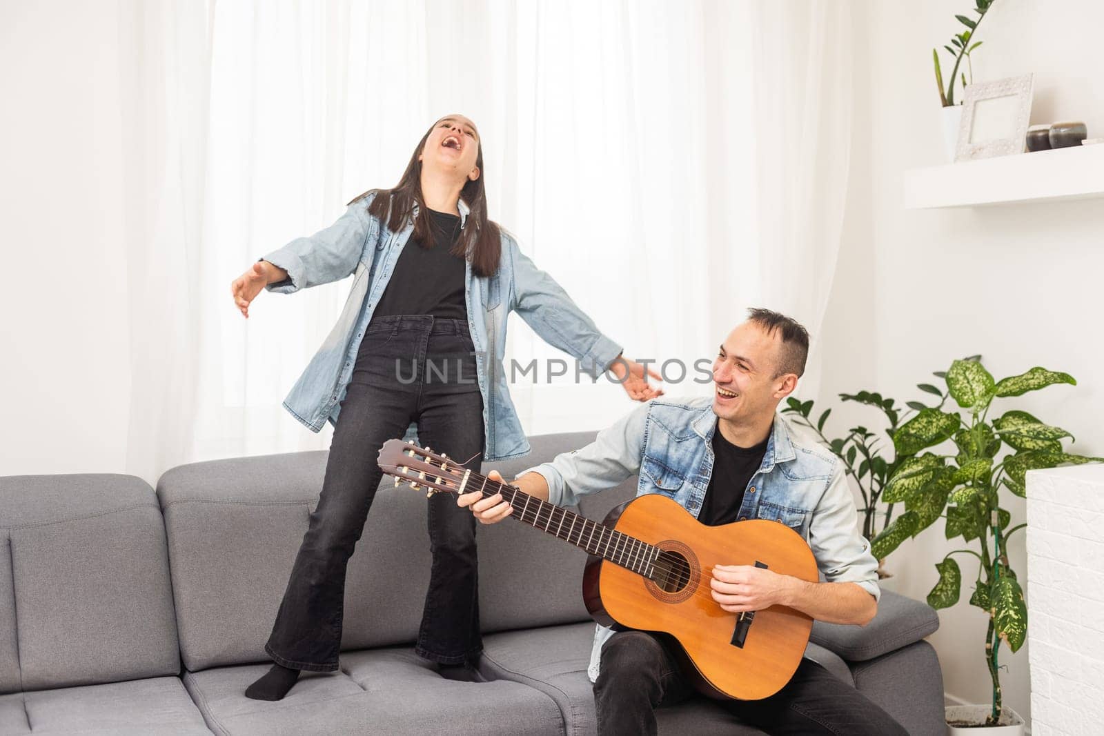 smiling father showing daughter how to play barre chord by Andelov13