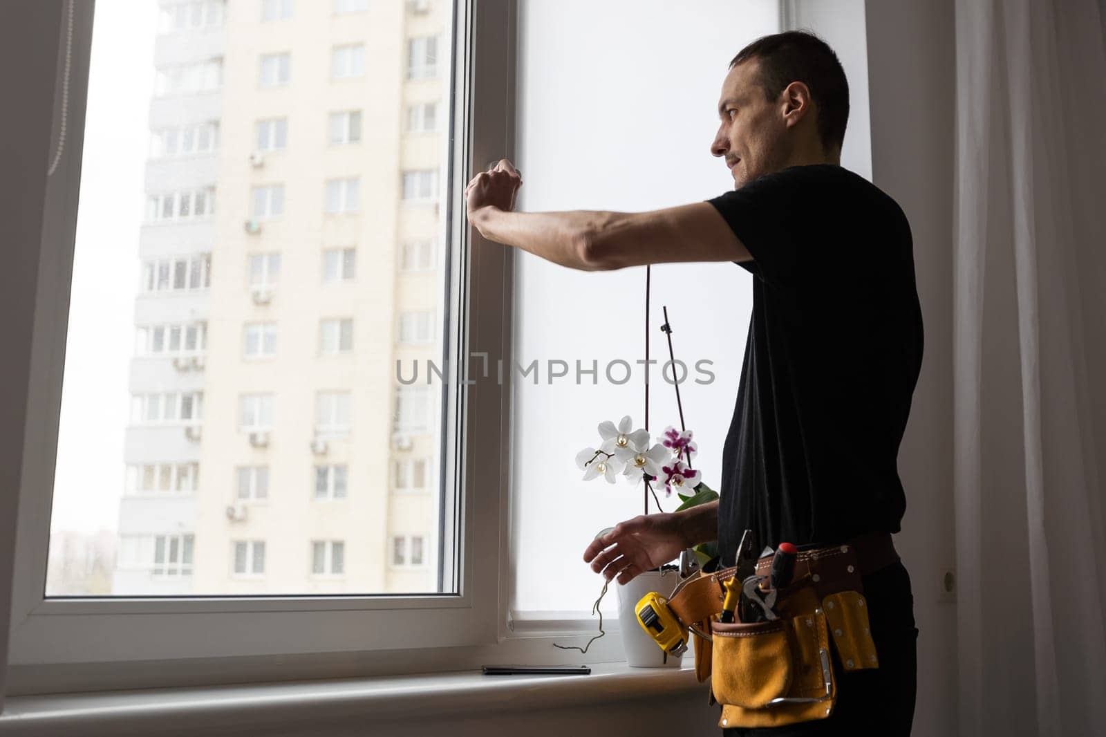 Master in gloves adjusting pvc windows with screwdriver closeup. Installation of plastic windows repair and maintenance concept by Andelov13