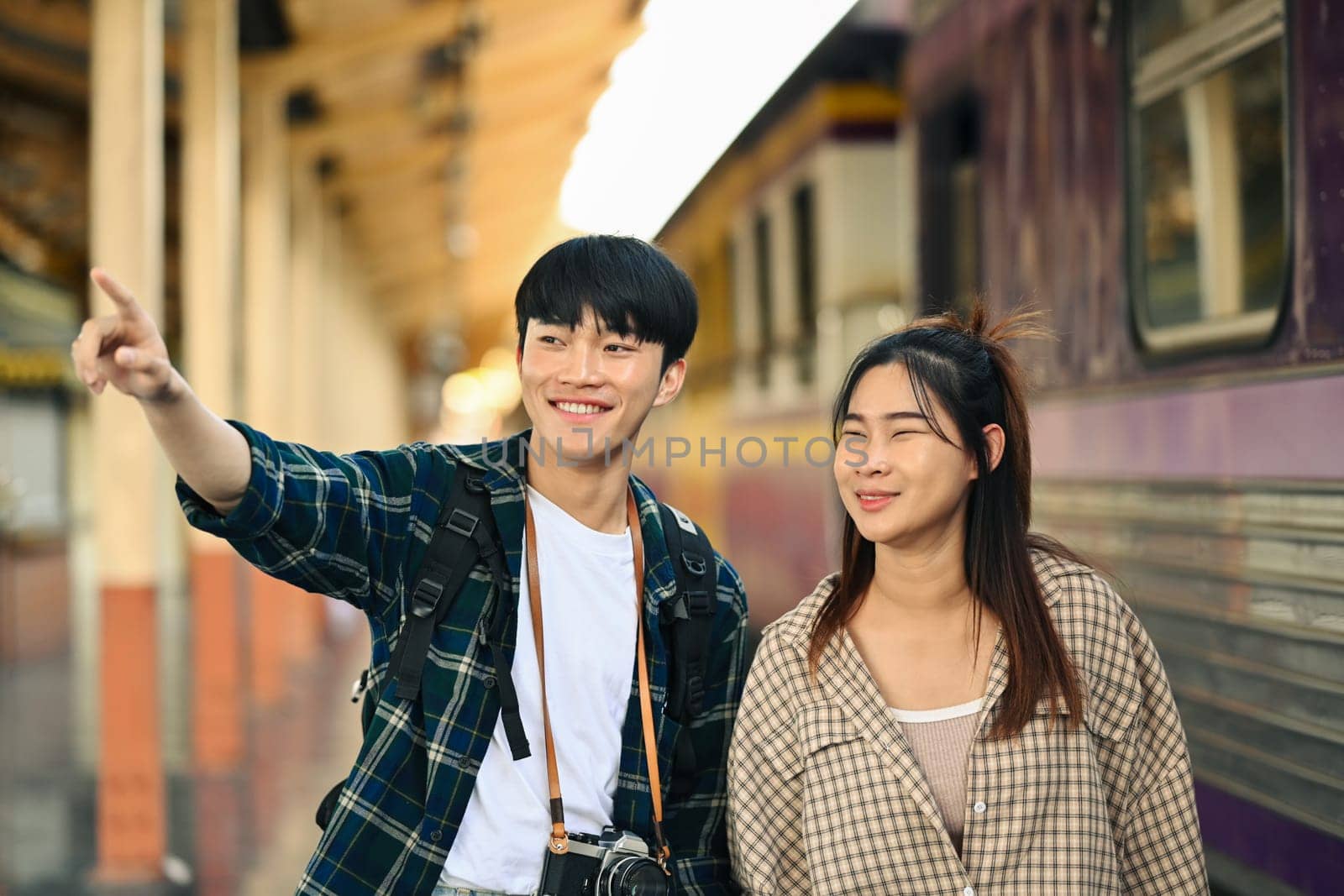 Happy young couple walking at railroad station platform. Travel and vacations concept by prathanchorruangsak