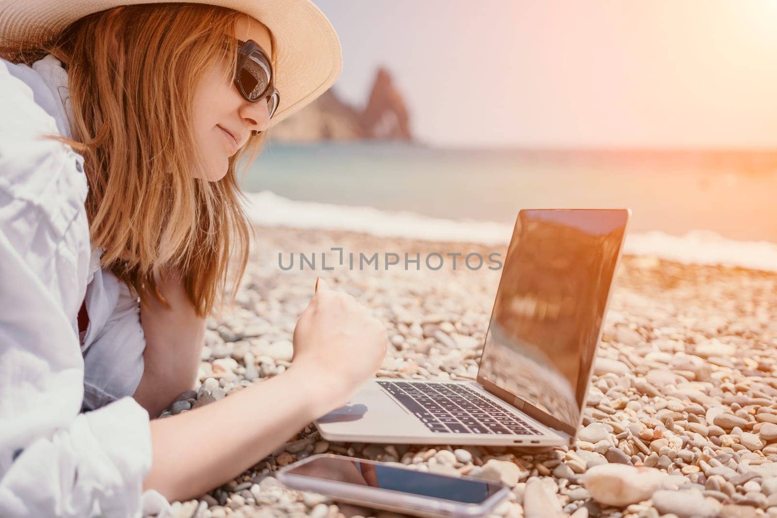 Woman sea laptop. Business woman in yellow hat working on laptop by sea. Close up on hands of pretty lady typing on computer outdoors summer day. Freelance, digital nomad, travel and holidays concept