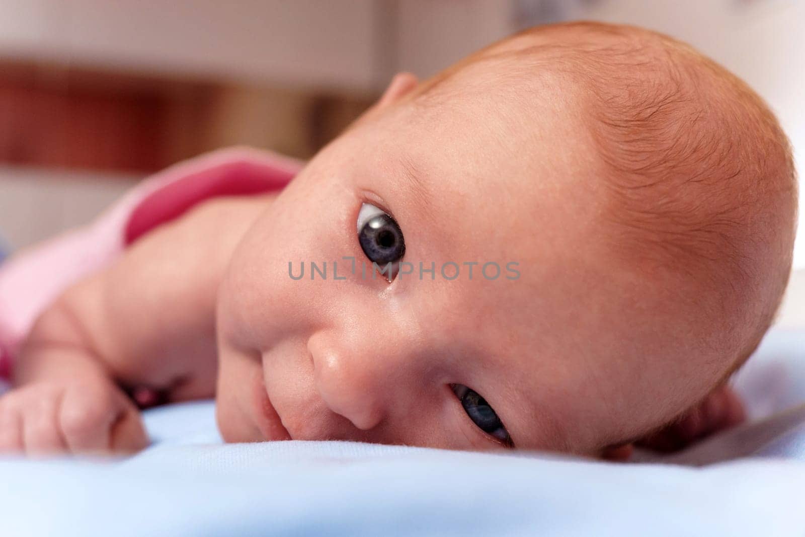 Newborn baby, at the tender age of two months, lies comfortably while curiously looking at the world around with bright, expressive eyes. by darksoul72