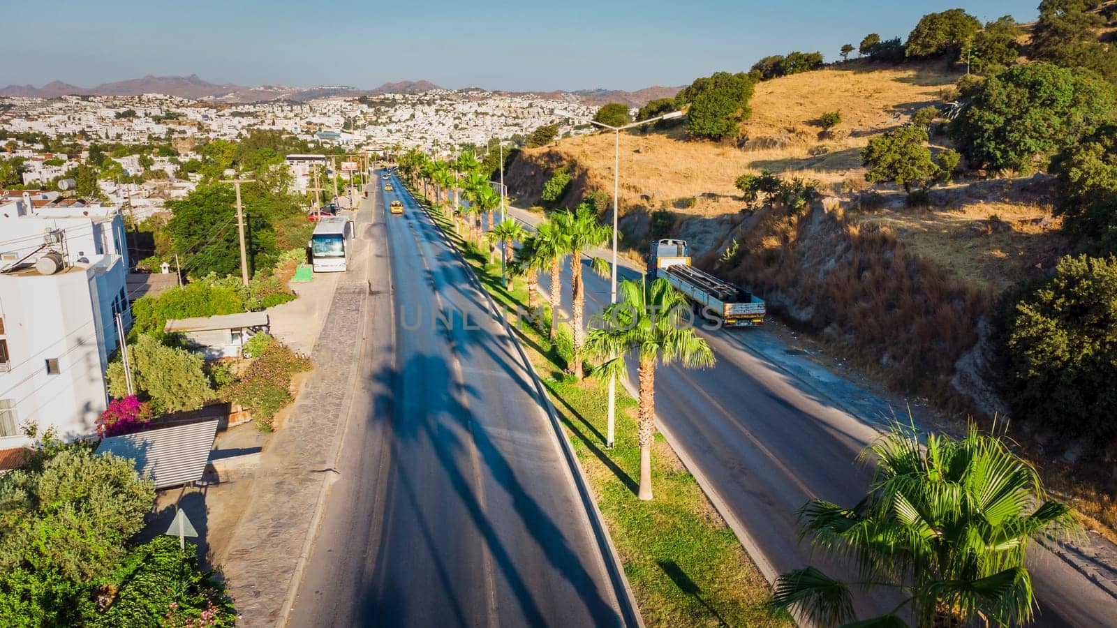 Road in tropical city. Landscape with rocks, sunny sky with clouds and beautiful asphalt road in the evening in summer.Travel background. Transportation. download image