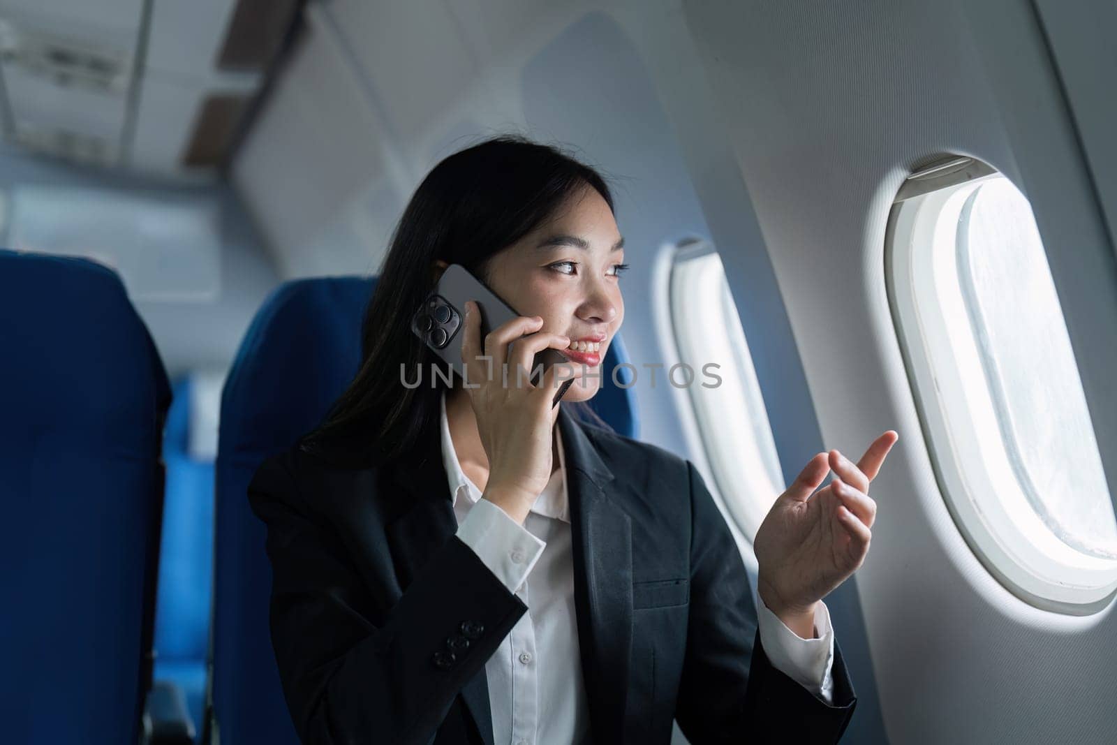Beautiful Asian businesswoman talking with mobile phone in aeroplane. working, travel, business concept.
