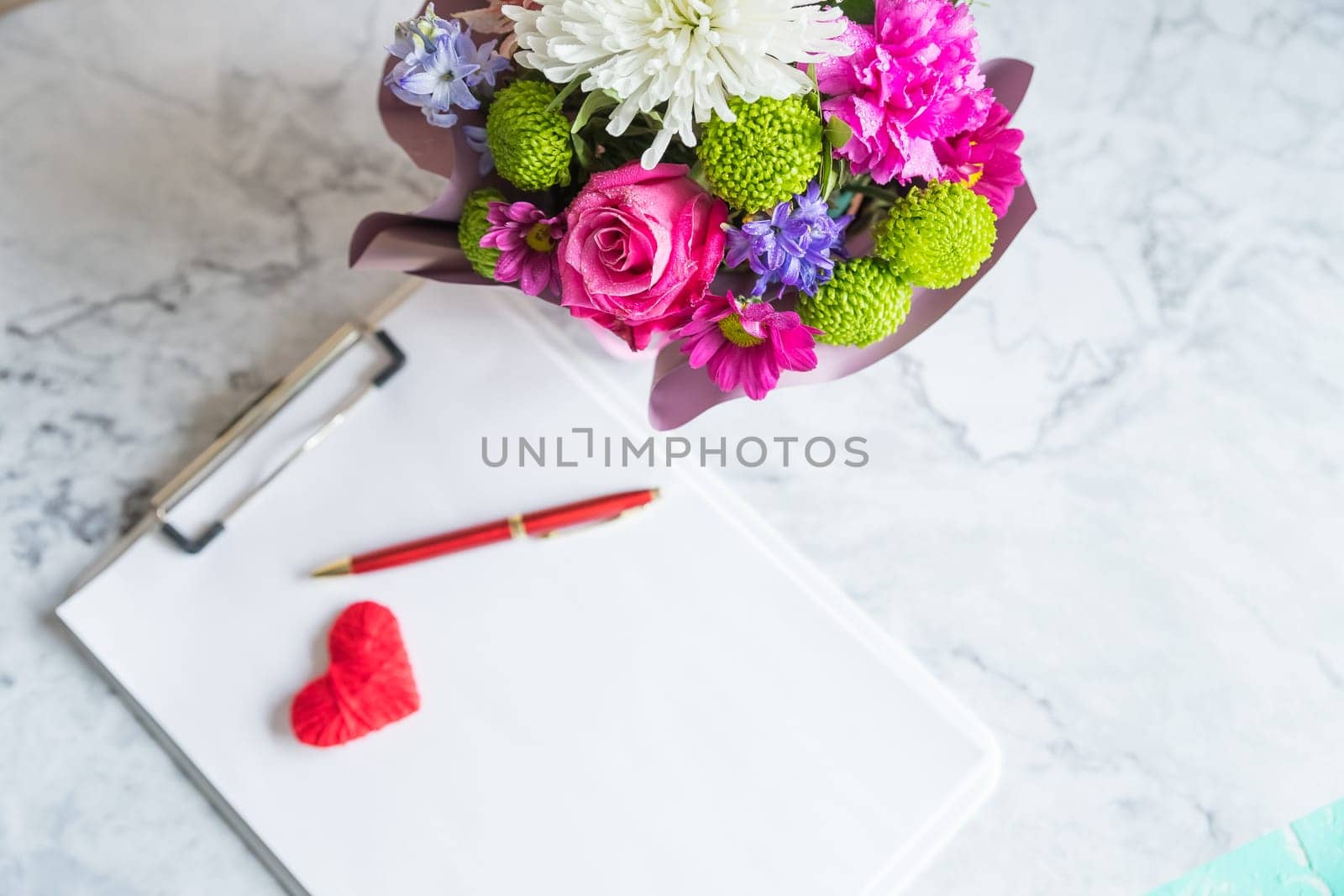 Bouquet of red roses and an envelope with a note on a white back