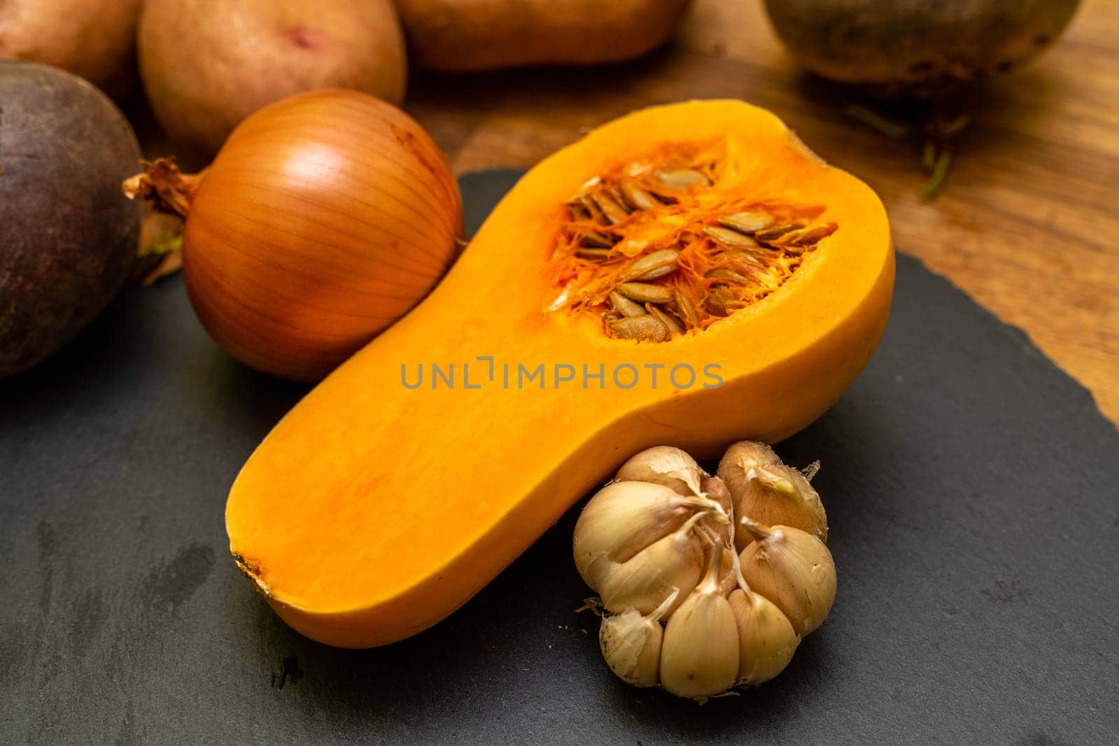 Orange pumpkin and garlic vegetable on a black background. Head of garlic. Halloween holiday. Agriculture food photo, background image. by Matiunina