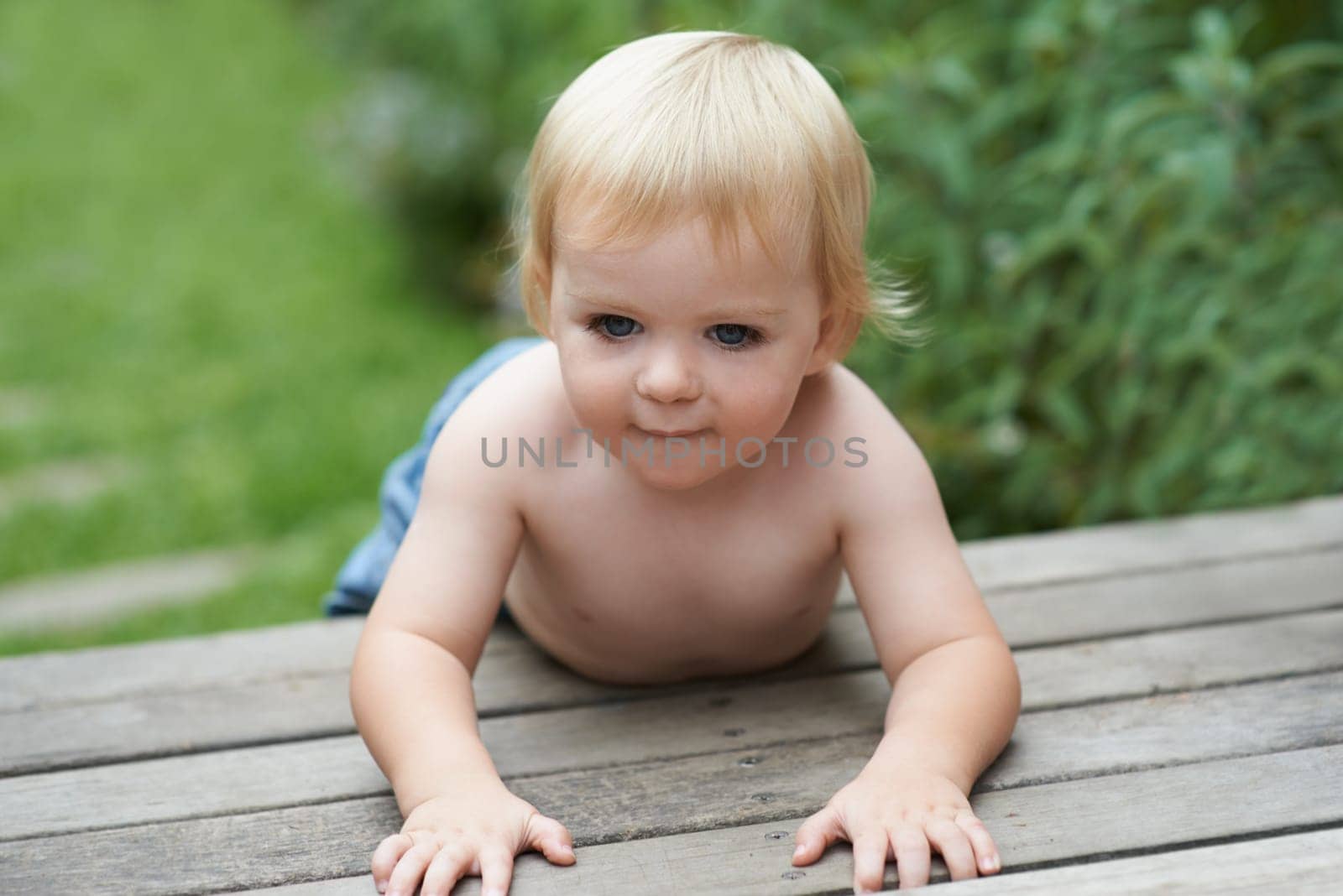 Baby, relax and floor outdoor for development with playing, curiosity or early childhood in backyard of home. Toddler, child and crawling on ground for wellness, milestone or exploring with innocence.