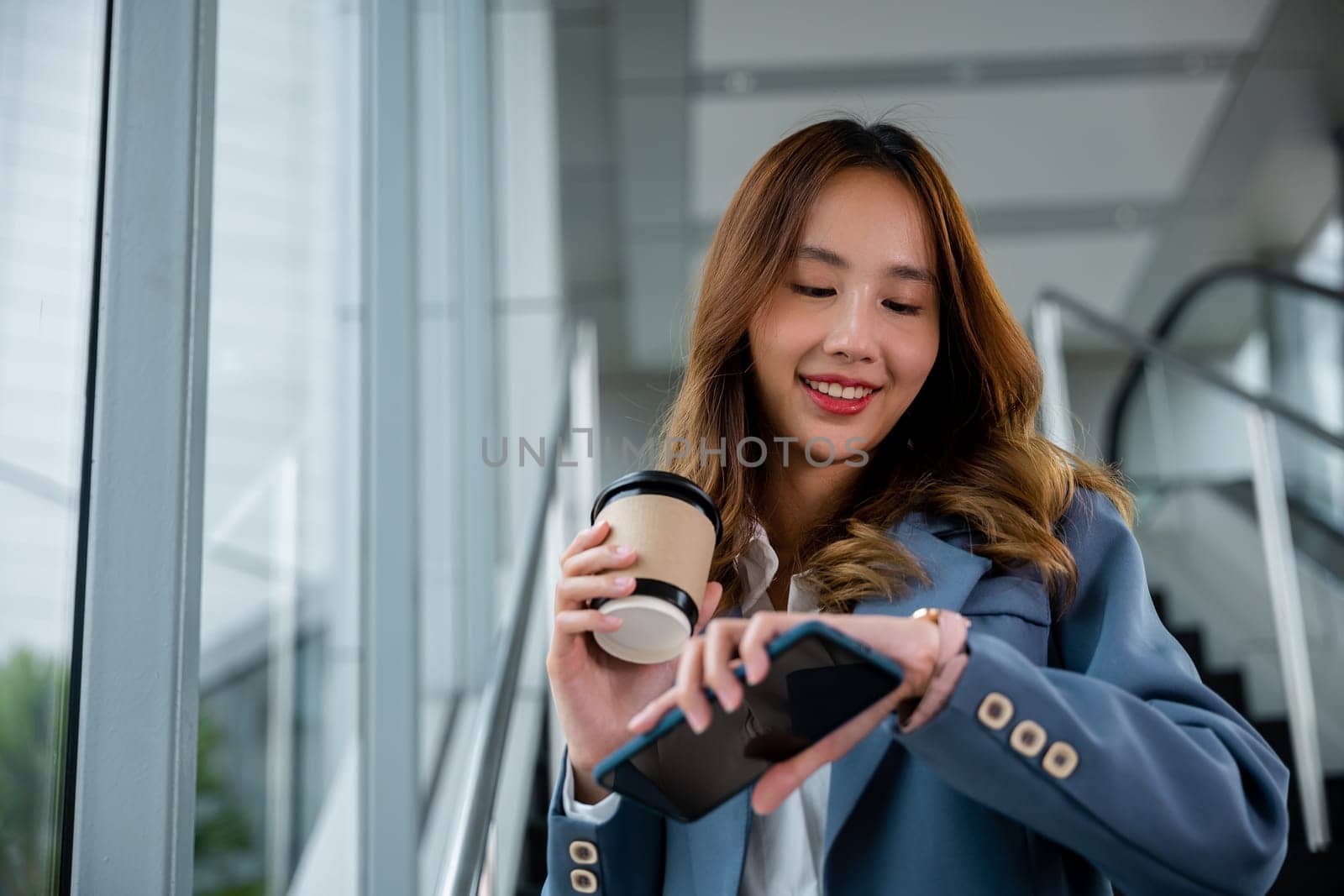 Woman holding a cup of coffee and a mobile device, multitasking on-the-go. Modern and convenient lifestyle. Perfect for lifestyle and communication themes.