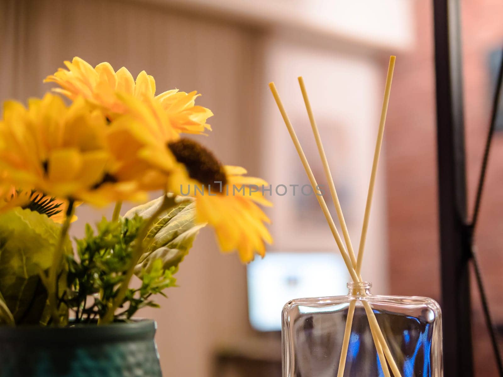 close up of reed diffuser and house faux flowers on wooden shelf. room freshener and decoration