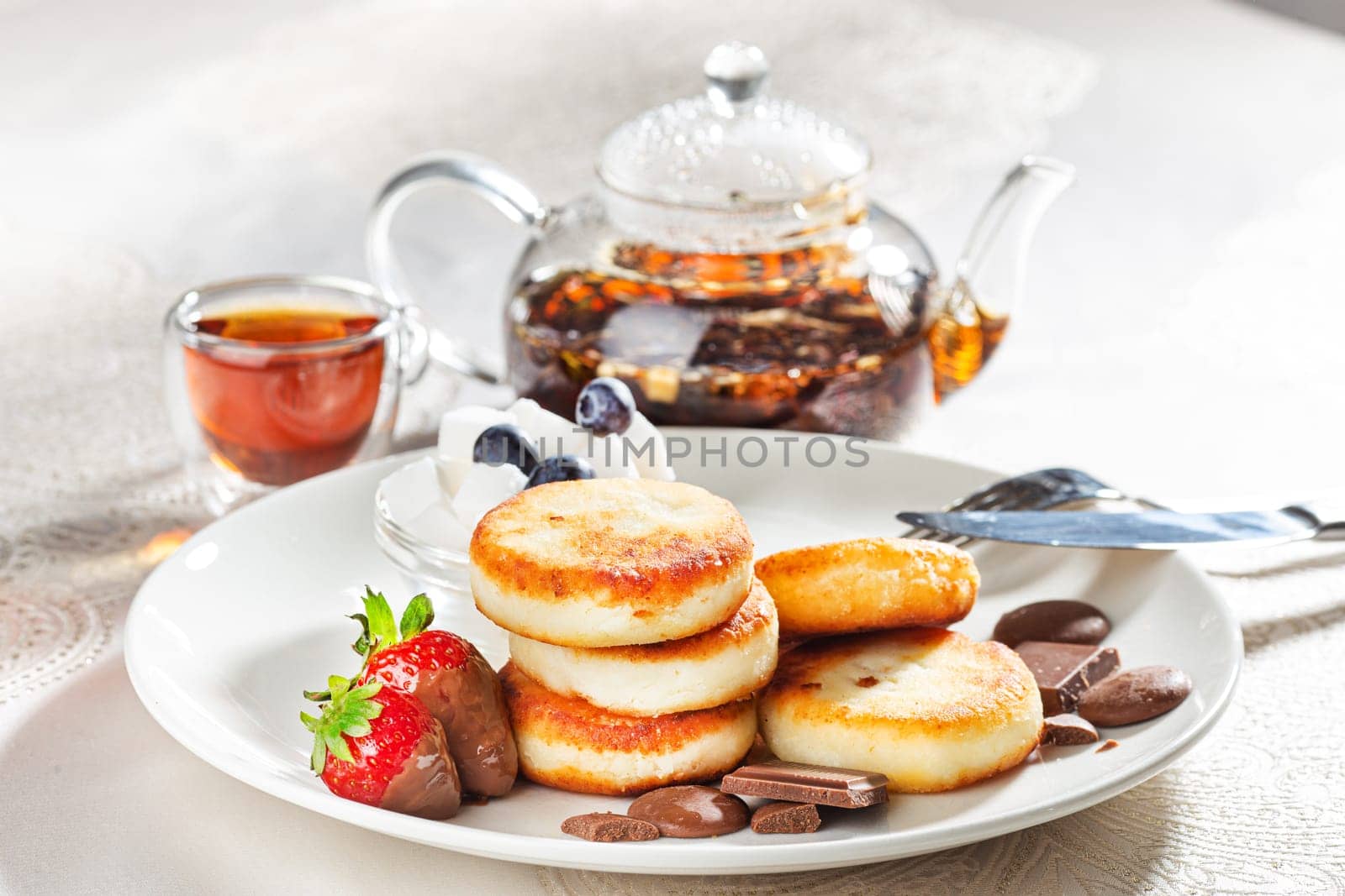 Cottage cheese pastries with strawberry, syrniki stuffed with chocolate on a white plate, selective focus by Gravika