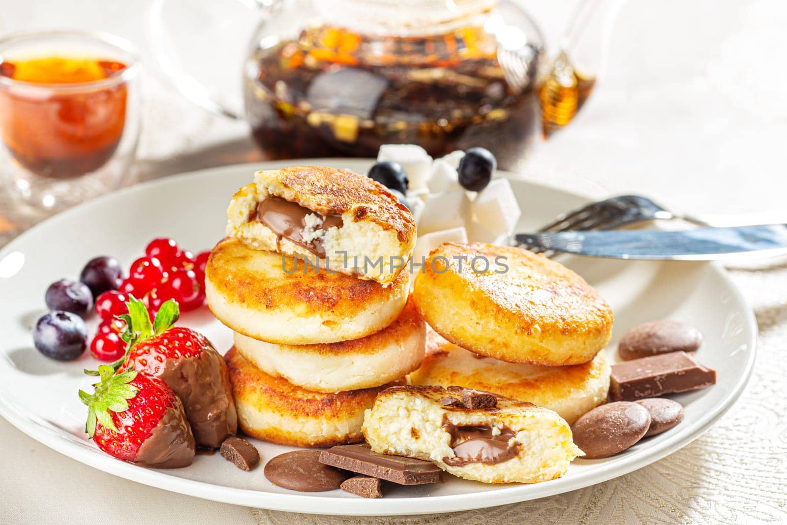 Cottage cheese pastries with strawberry, syrniki stuffed with chocolate on a white plate, selective focus by Gravika