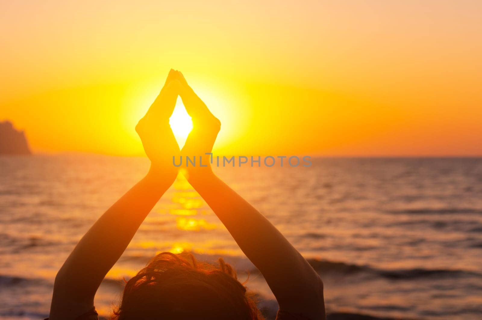 Woman's hands symbolizing prayer and gratitude. Mudra. Yoga concept. Silhouette of female hands on sun background. Beautiful scene.