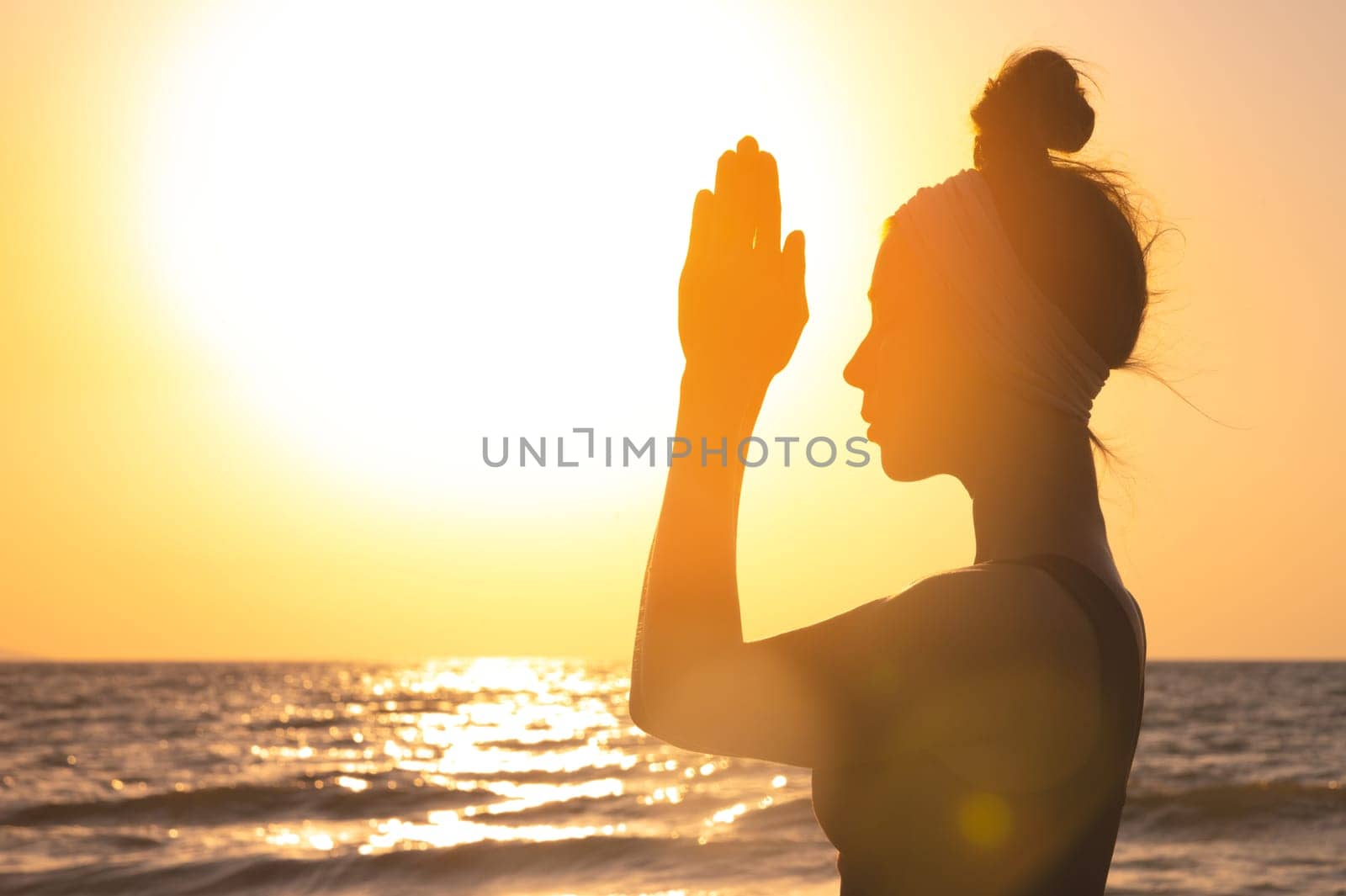 Happy woman silhouette, raises her hands to the sun at dawn. Freedom and spirituality concept.