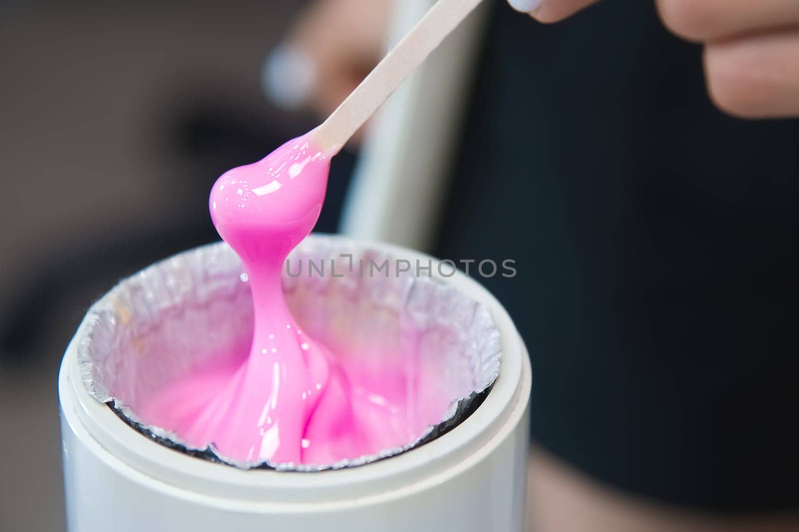 depilation and beauty, sugar paste or wax for hair removal. Preparation of pink wax for sugaring. Close-up of sugar paste or wax honey for hair removal using a wooden wax spatula.