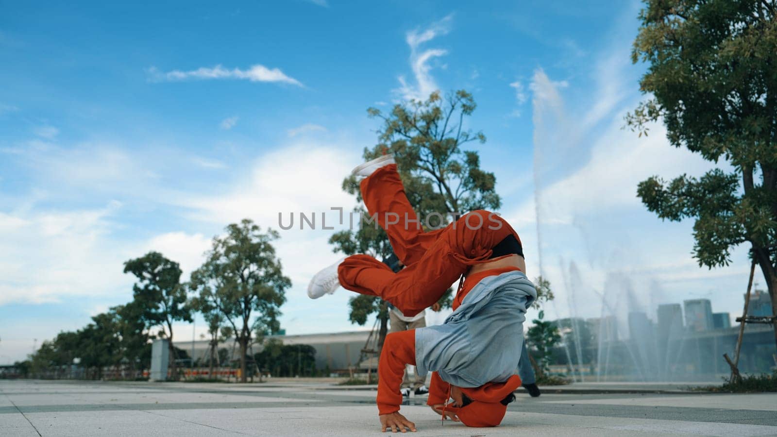 Asian skilled hipster doing freeze pose at camera surrounded by break dancer team near fountain with sky background. Group of handsome people practice b-boy dance. Outdoor sport 2024. Sprightly.