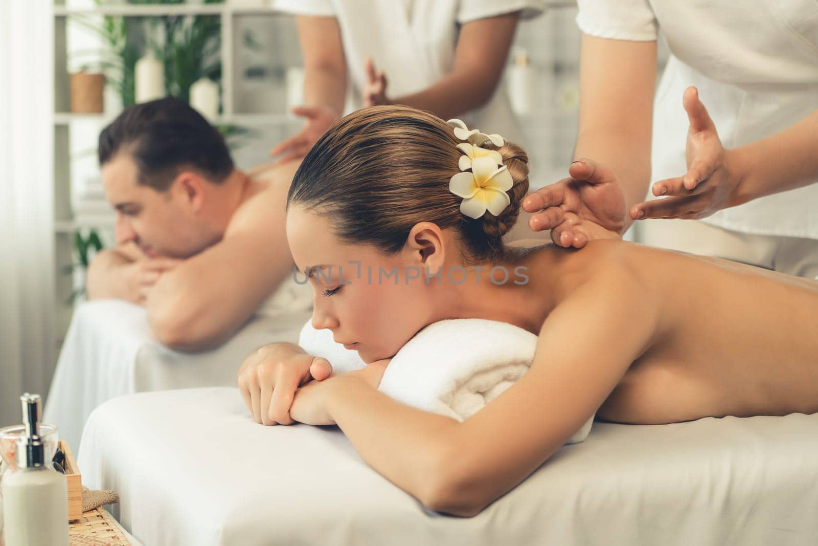 Caucasian couple customer enjoying relaxing anti-stress spa massage and pampering with beauty skin recreation leisure in day light ambient salon spa at luxury resort or hotel. Quiescent