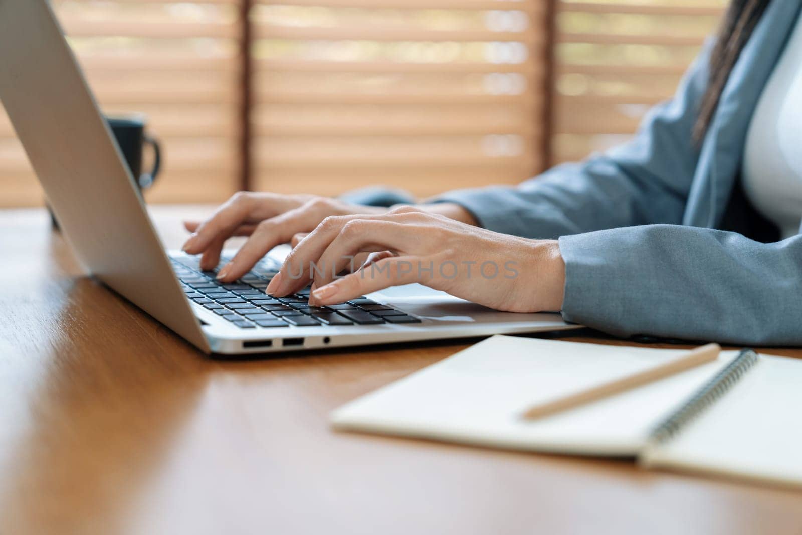 Businesswoman typing on laptop, working on business on workspace table. Young college student study or brainstorming strategic plan in office workplace for business success. Blithe