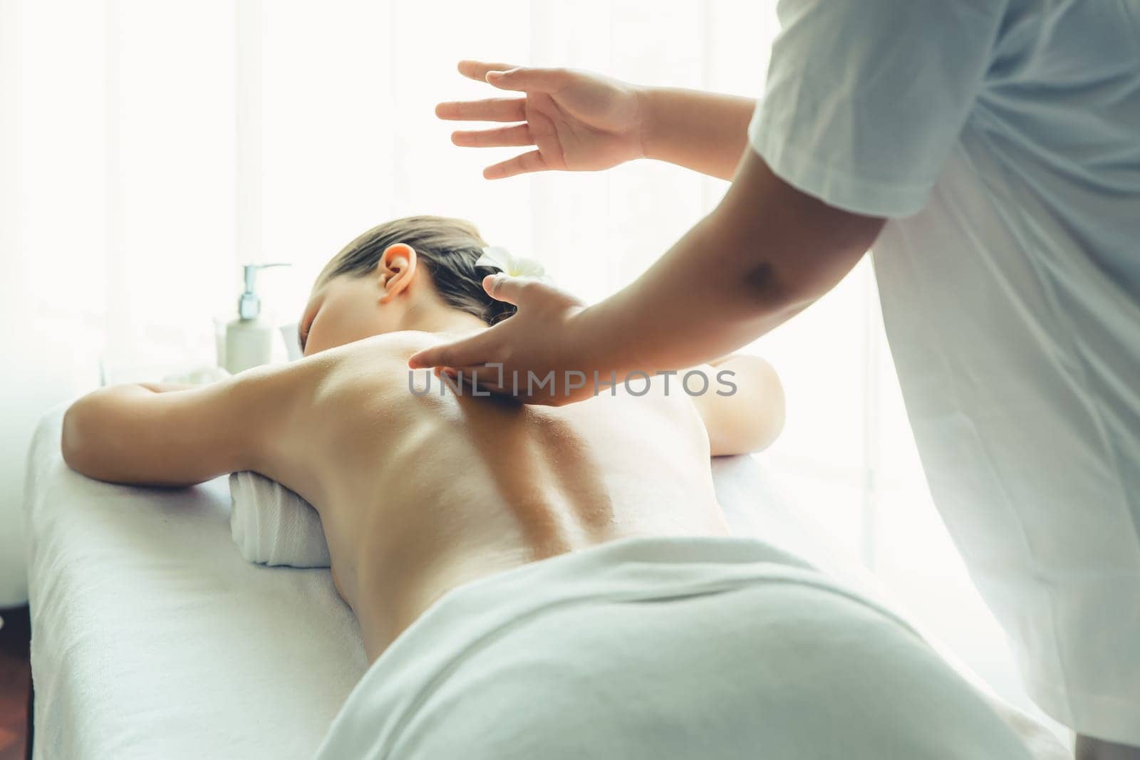 Caucasian woman customer enjoying relaxing anti-stress spa massage and pampering with beauty skin recreation leisure in day light ambient salon spa at luxury resort or hotel. Quiescent