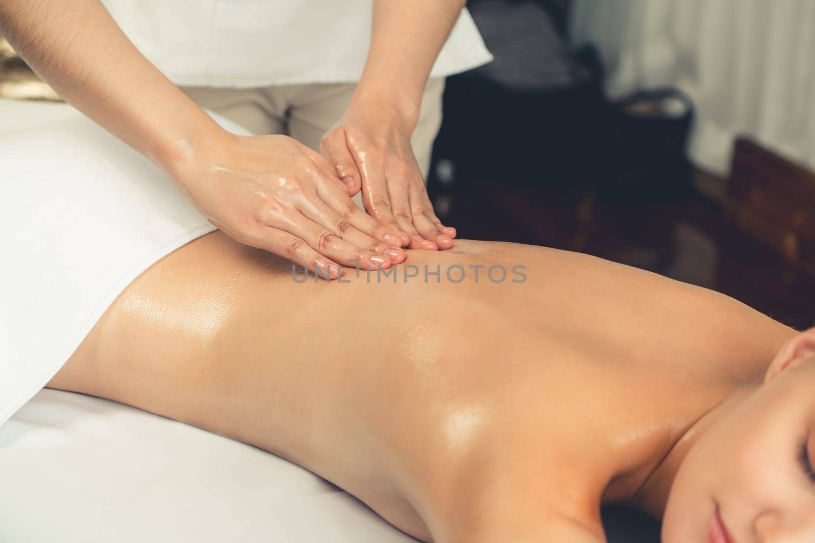 Closeup woman customer enjoying relaxing anti-stress spa massage and pampering with beauty skin recreation leisure in day light ambient salon spa at luxury resort or hotel. Quiescent