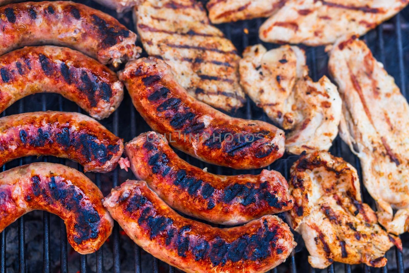 Pork meat and sausages grilled on a charcoal barbeque. Top view of tasty barbecue, food concept, food on grill and detail of food on the grill by vladispas