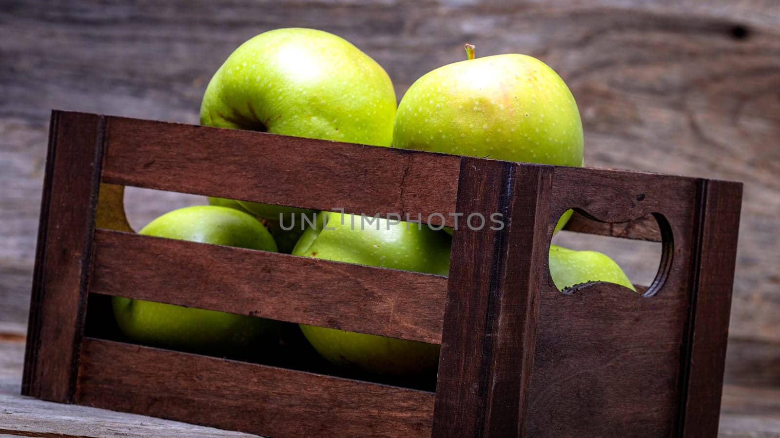 Wooden crate with ripe green apples on wooden table. by vladispas