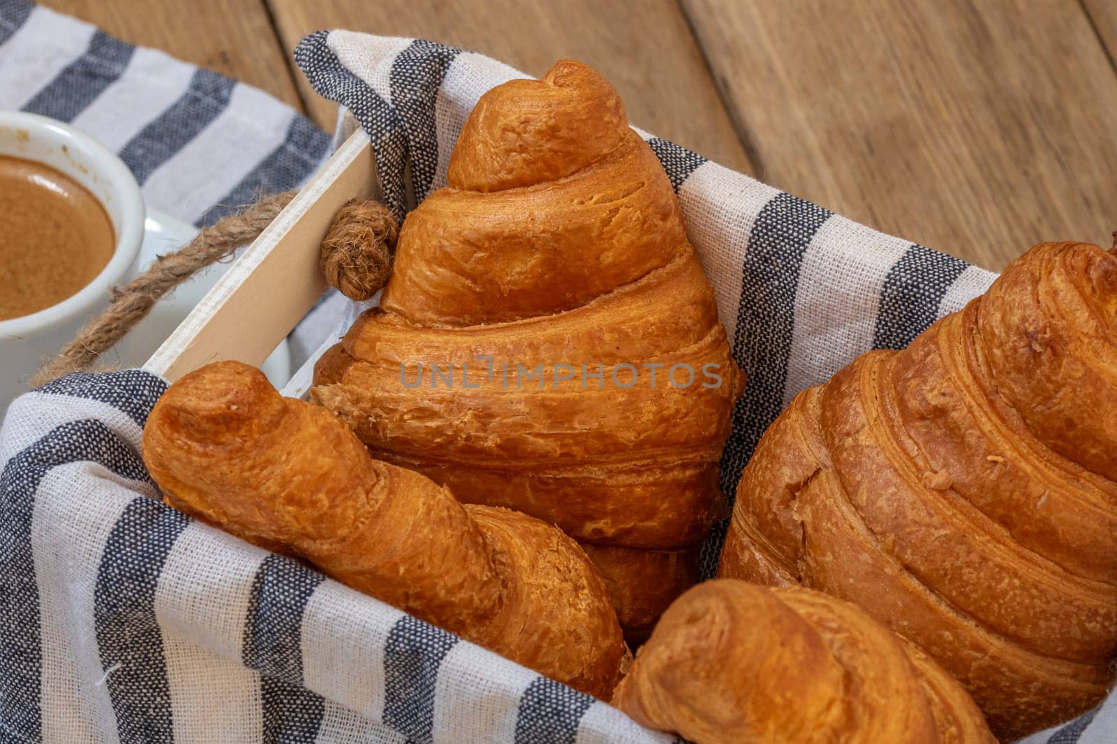 Puff pastry, coffee cup and buttered French croissant on wooden crate. Food and breakfast concept. Detail of coffee desserts and fresh pastries by vladispas