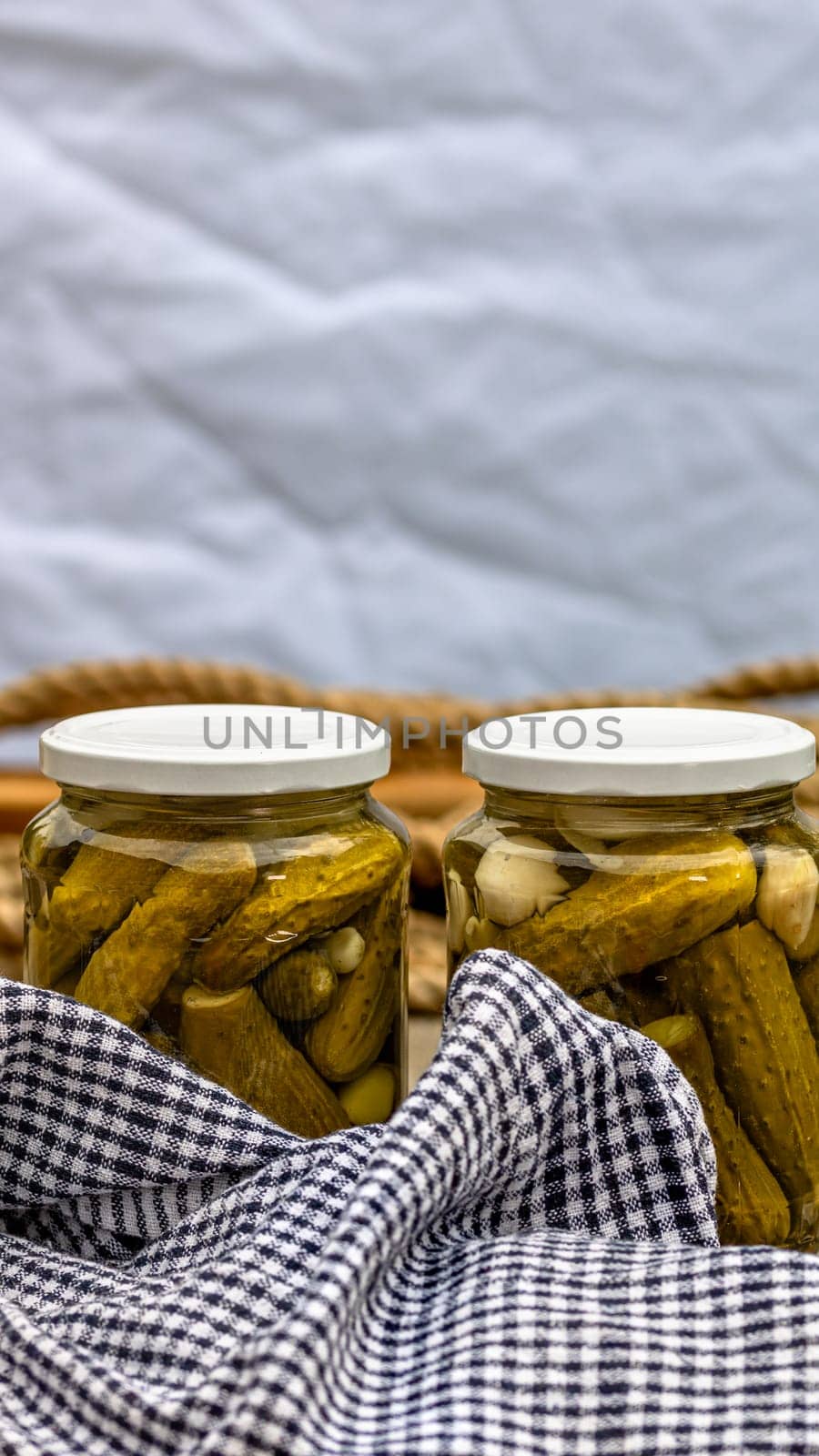 Glass jars with pickled red bell peppers and pickled cucumbers (pickles) isolated. Jars with variety of pickled vegetables. Preserved food concept in a rustic composition. by vladispas