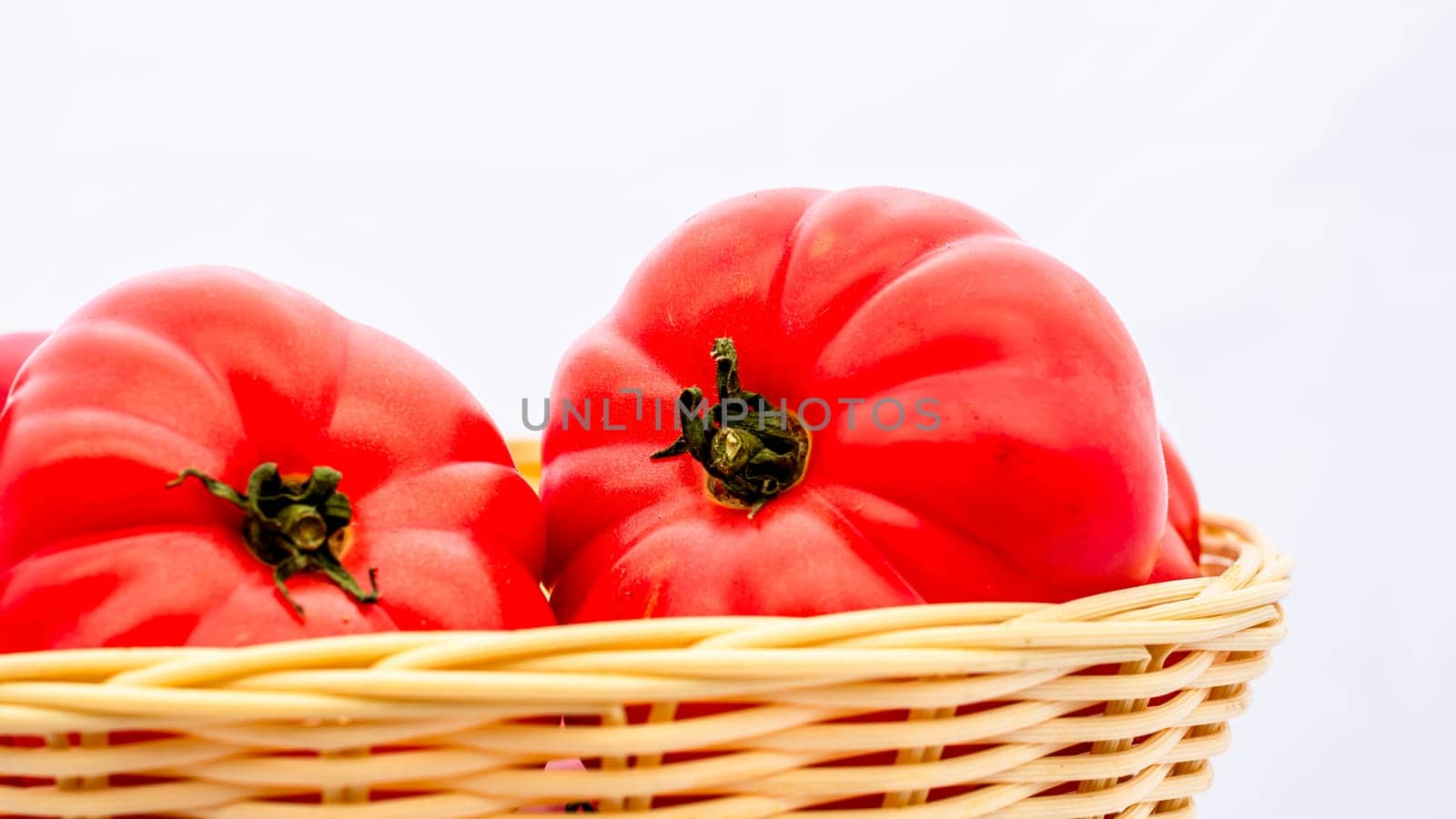 Fresh and tasty red tomatoes in wicker basket isolated by vladispas