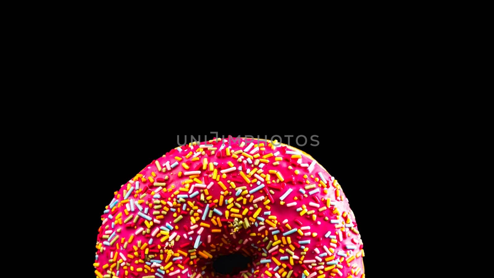 Pink glazed donut with sprinkles isolated. Close up of colorful donut. by vladispas