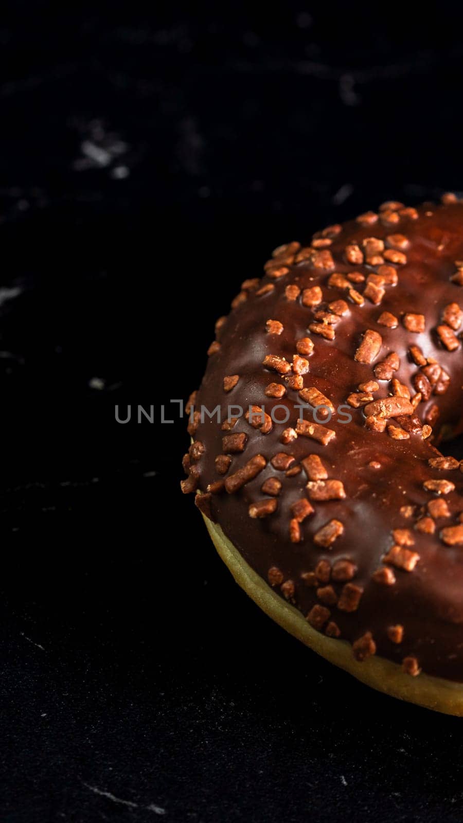 Chocolate glazed donut with chocolate chips isolated. Close up of delicious donut.