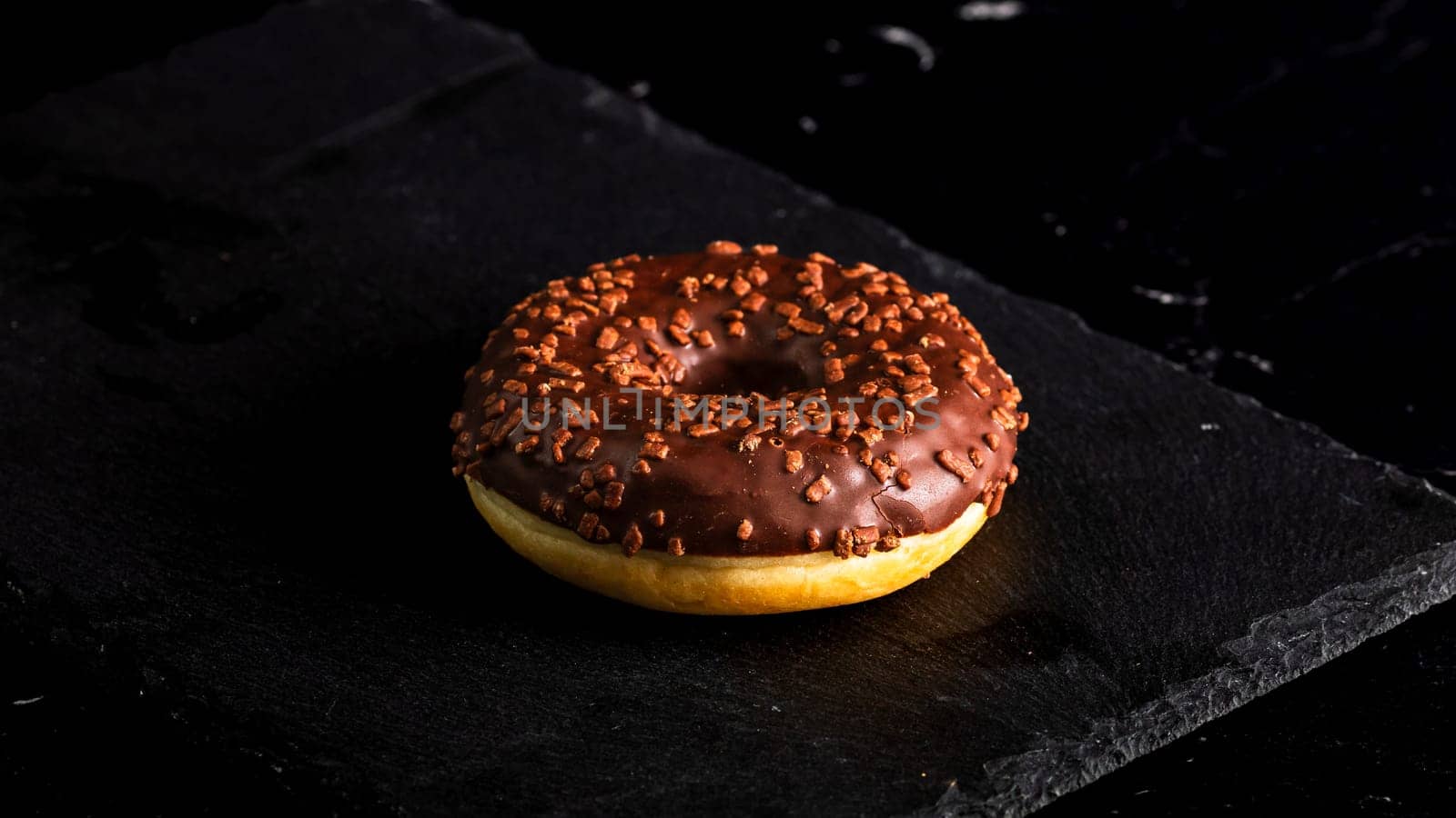Chocolate glazed donut with chocolate chips isolated. Close up of delicious donut. by vladispas