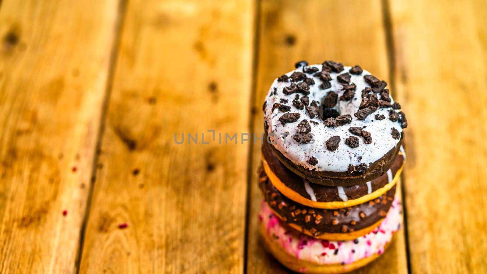 Colorful donuts on wooden table. Sweet icing sugar food with glazed sprinkles, doughnut with chocolate frosting. Top view with copy space