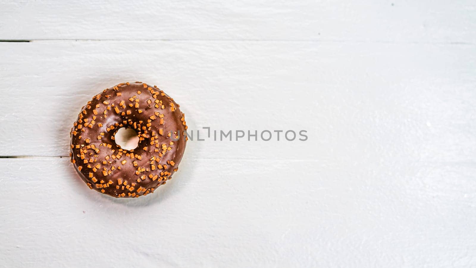 Colorful donuts on white wooden table. Sweet icing sugar food with glazed sprinkles, doughnut with frosting. Top view with copy space