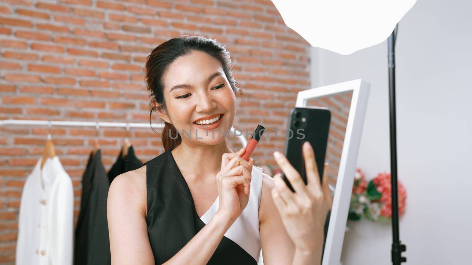 Woman influencer shoot live streaming vlog video review vivancy makeup social media or blog. Happy young girl with cosmetics studio lighting for marketing recording session broadcasting online.