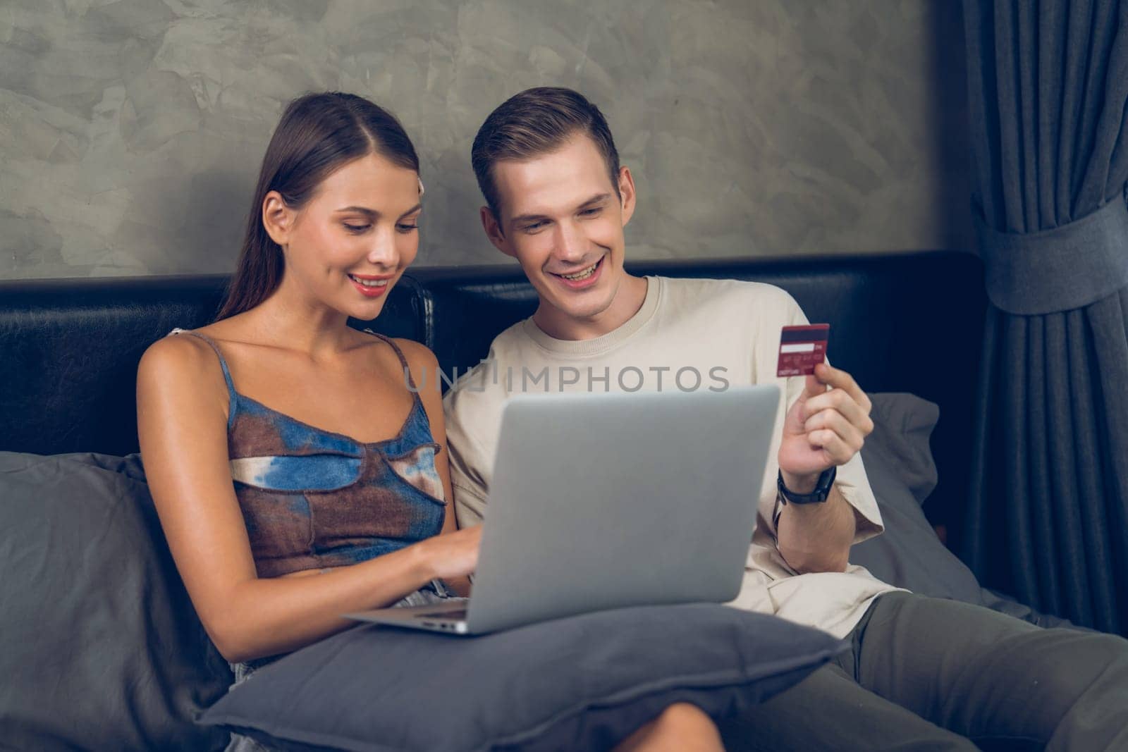 Young couple sit in the bed room using online payment app. Unveiling by biancoblue