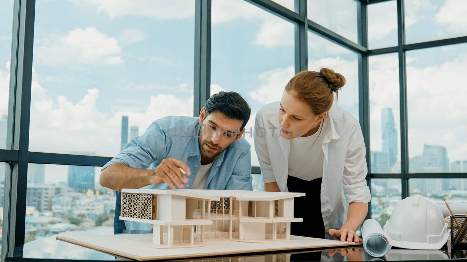 Cooperative architect engineer team working together to measure house model by using pencil. Successful caucasian interior designer team inspect architectural model construction. Design. Tracery