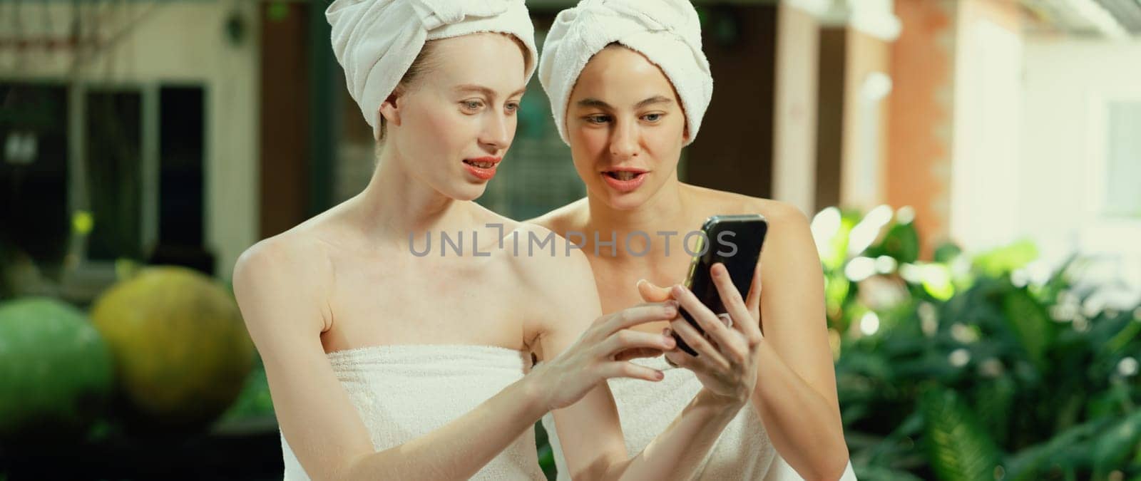 Couple of young beautiful women with beautiful skin in white towel taking a photo together at outdoor surrounded by peaceful natural environment. Beauty and healthy spa concept. Tranquility.